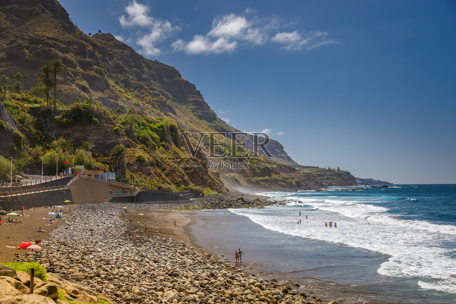 特内里费岛的索科罗海滩,展示了崎岖的海岸线、深蓝色的海浪和高耸的悬崖,悬崖上覆盖着绿色植被。照片摄影图片