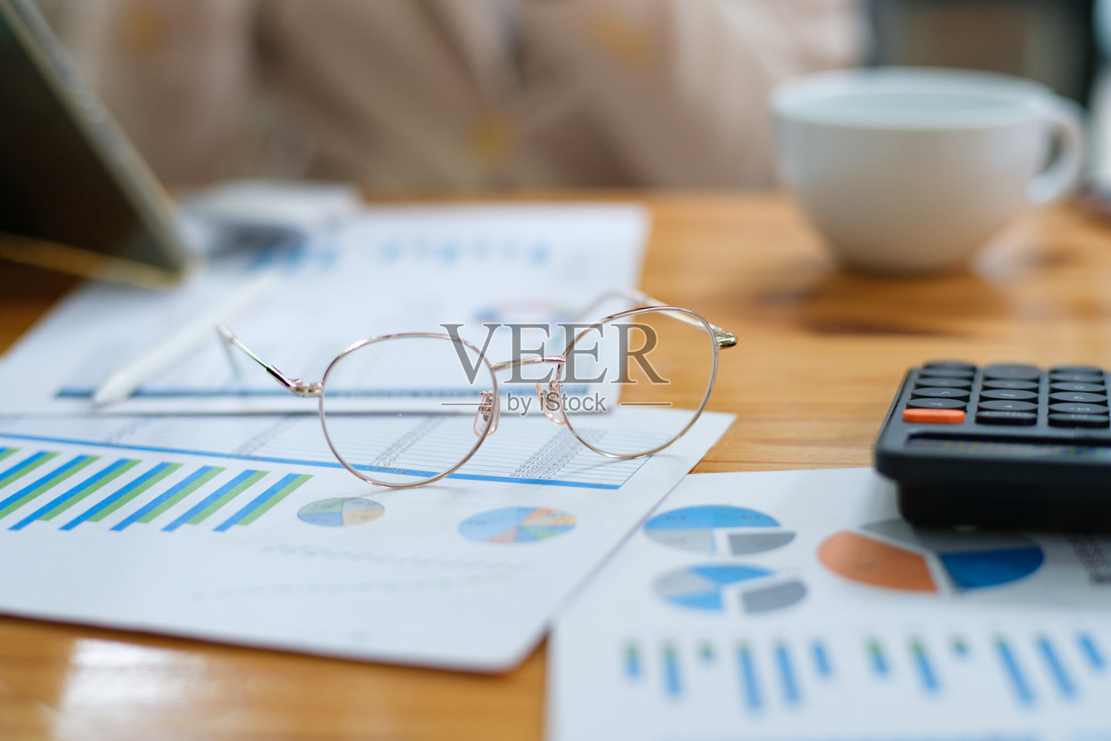 桌面上放着财务图表、眼镜和计算器,适合数据分析和规划的特写镜头照片摄影图片
