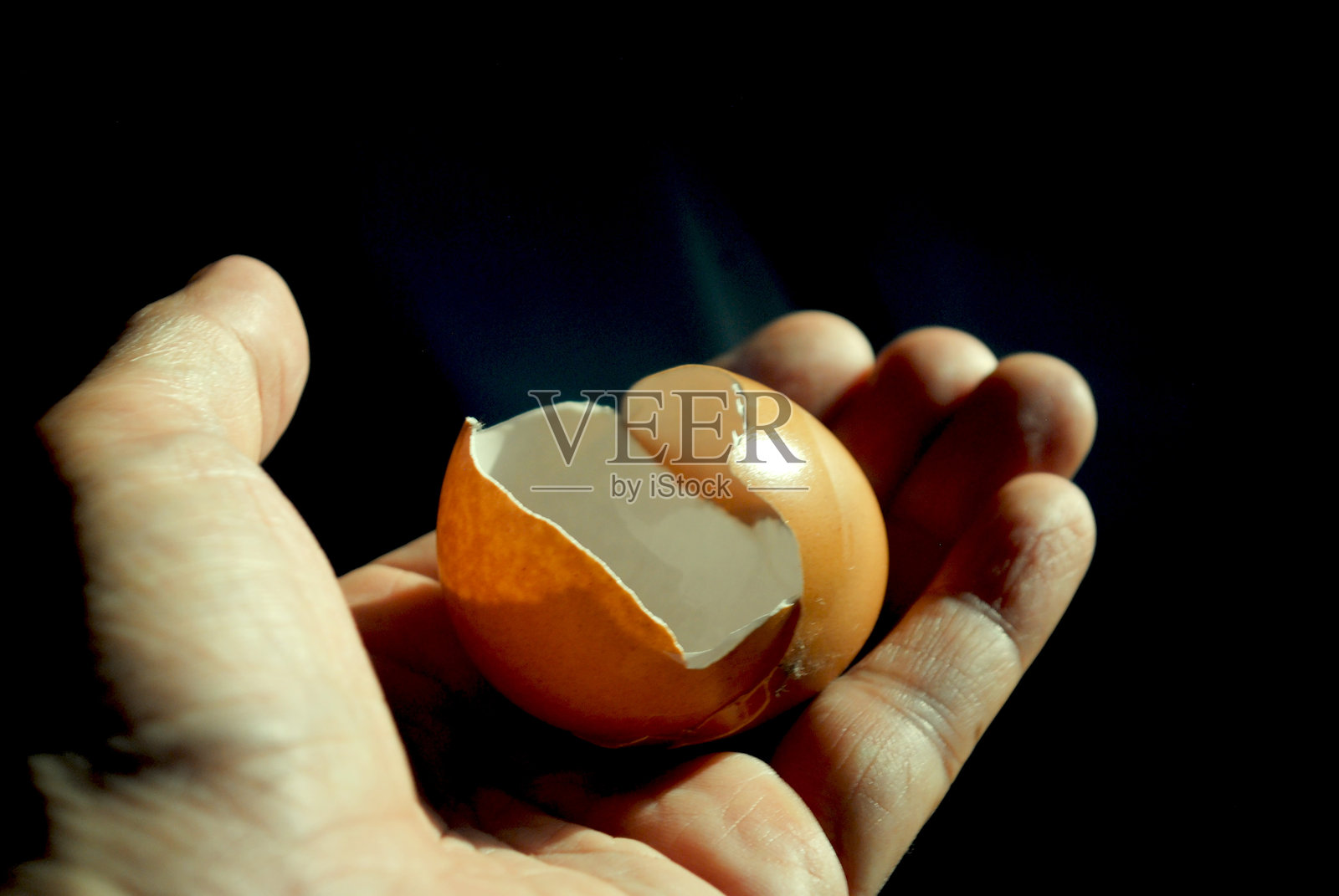 手中握着一个孤立的蛋壳。照片摄影图片