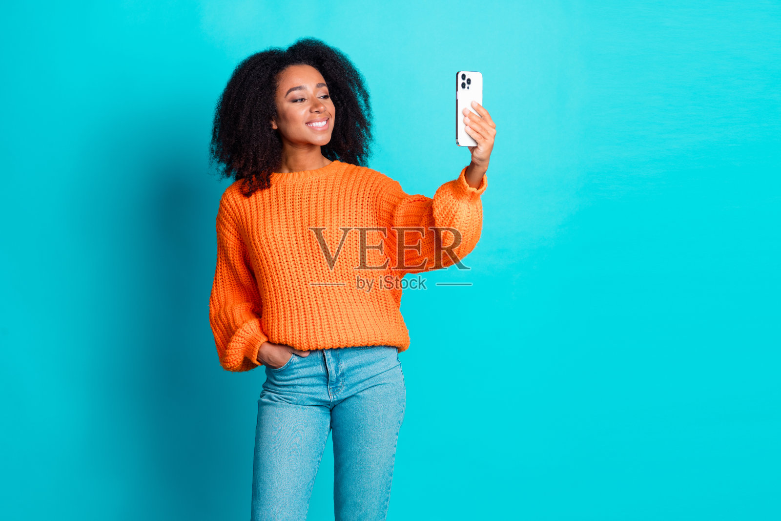 可爱的年轻女士在水蓝色背景下穿着时尚的橙色针织服装自拍照照片摄影图片