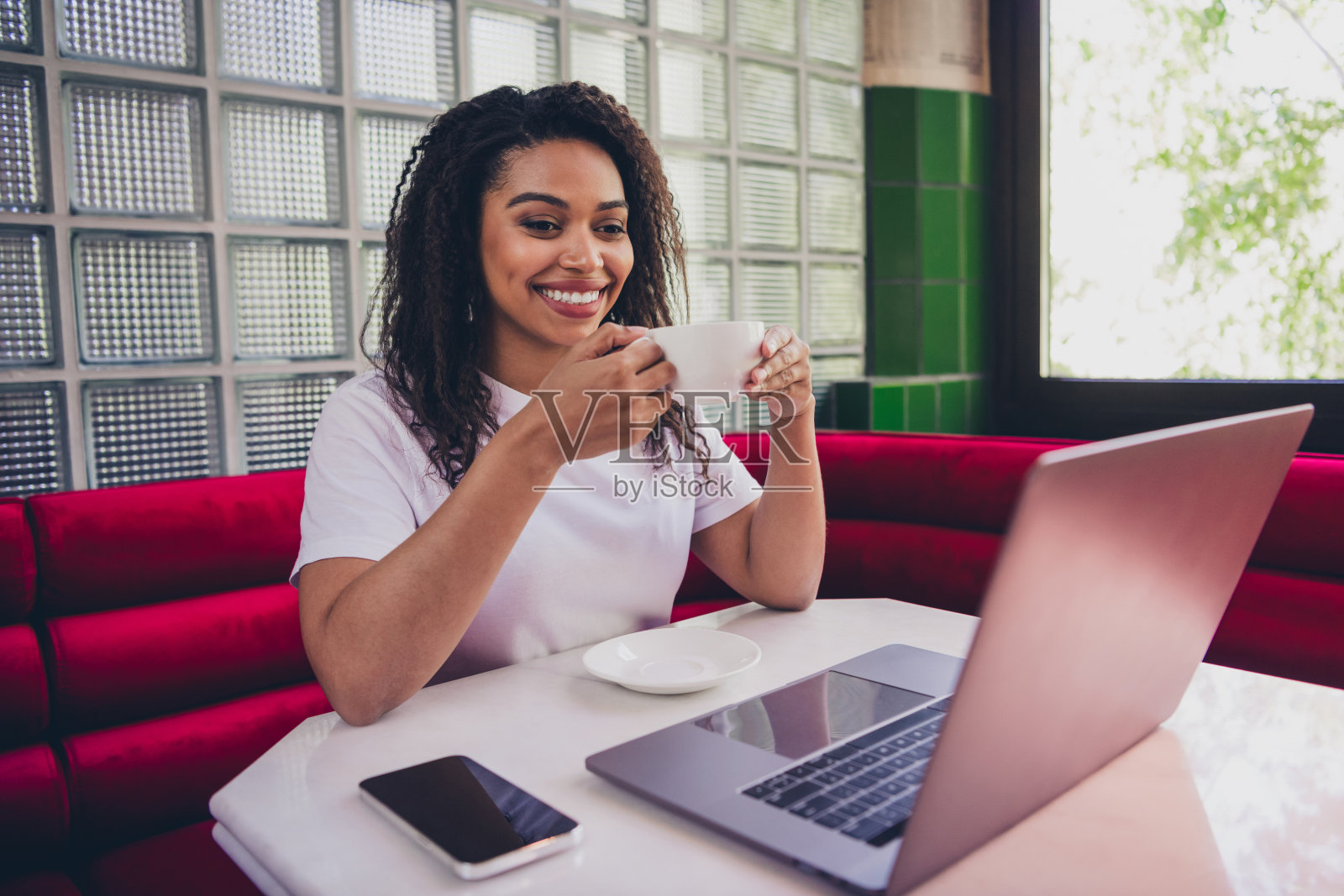 年轻的职场女性在现代商务中心咖啡馆室内喝咖啡并使用笔记本电脑的肖像照片摄影图片