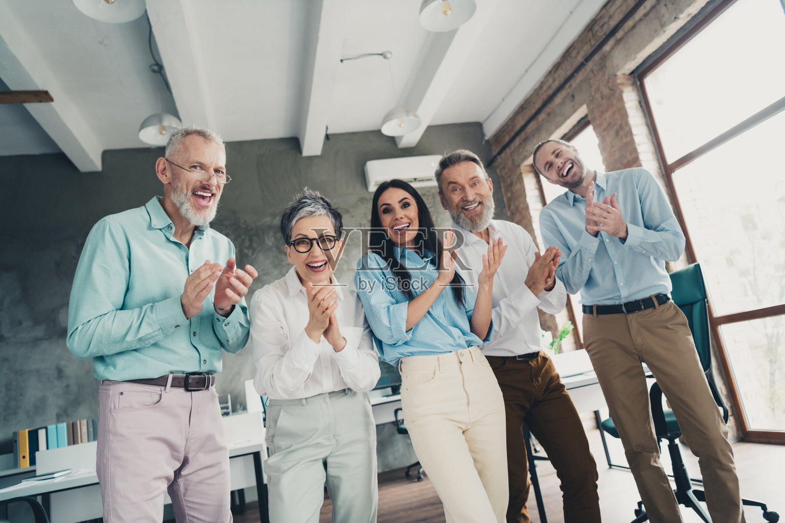 团队创业伙伴在舒适宜人的创意创业办公室内鼓掌祝贺照片摄影图片