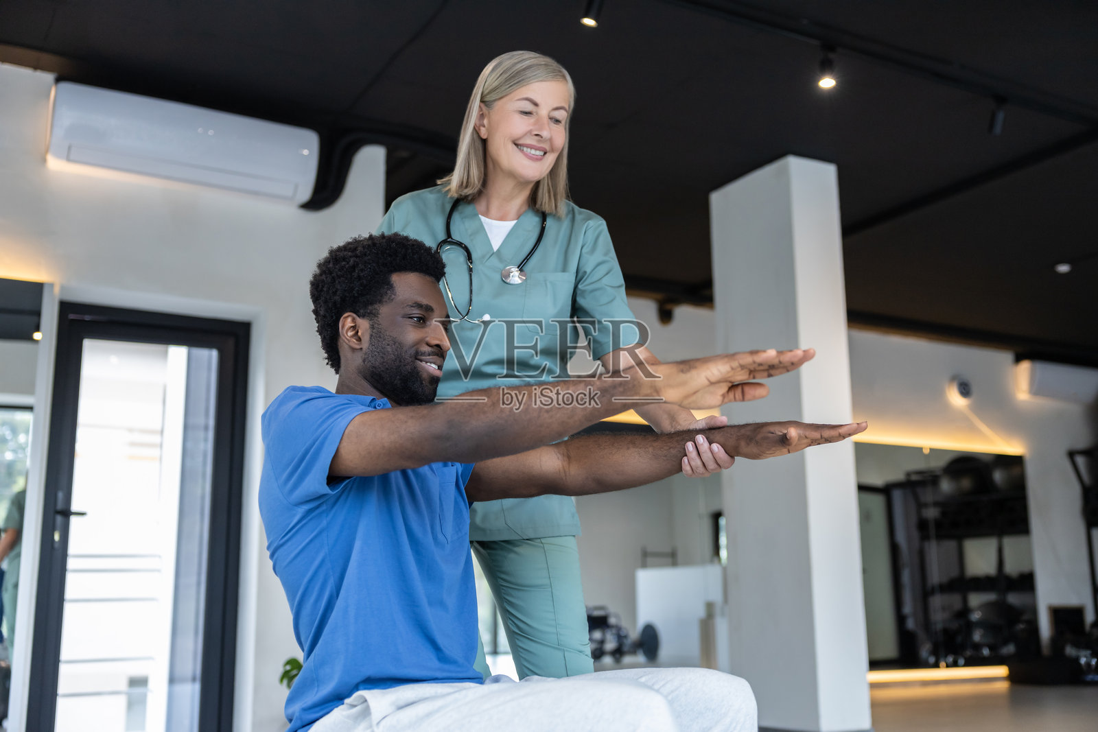 年轻男性患者在物理治疗师的指导下进行锻炼,伸展手臂。照片摄影图片