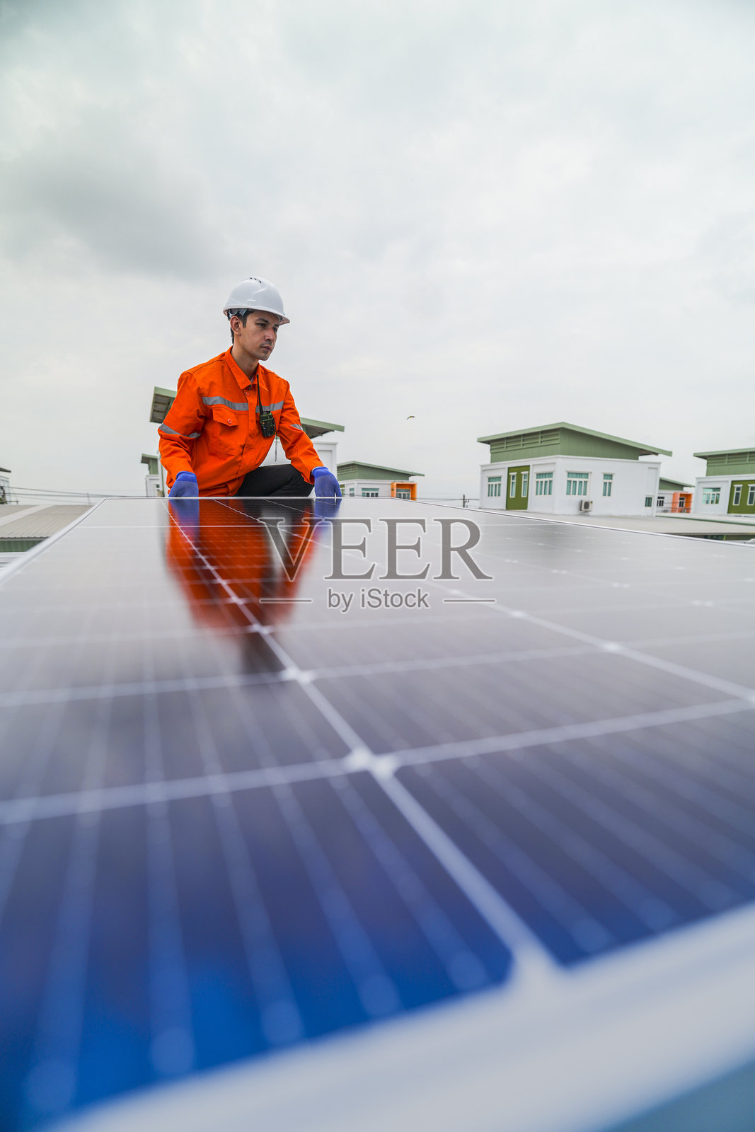 工程师检查太阳能电池板或光伏电池的施工,使用电子设备。工业可再生能源的绿色电力。工人在塔楼屋顶上工作。照片摄影图片