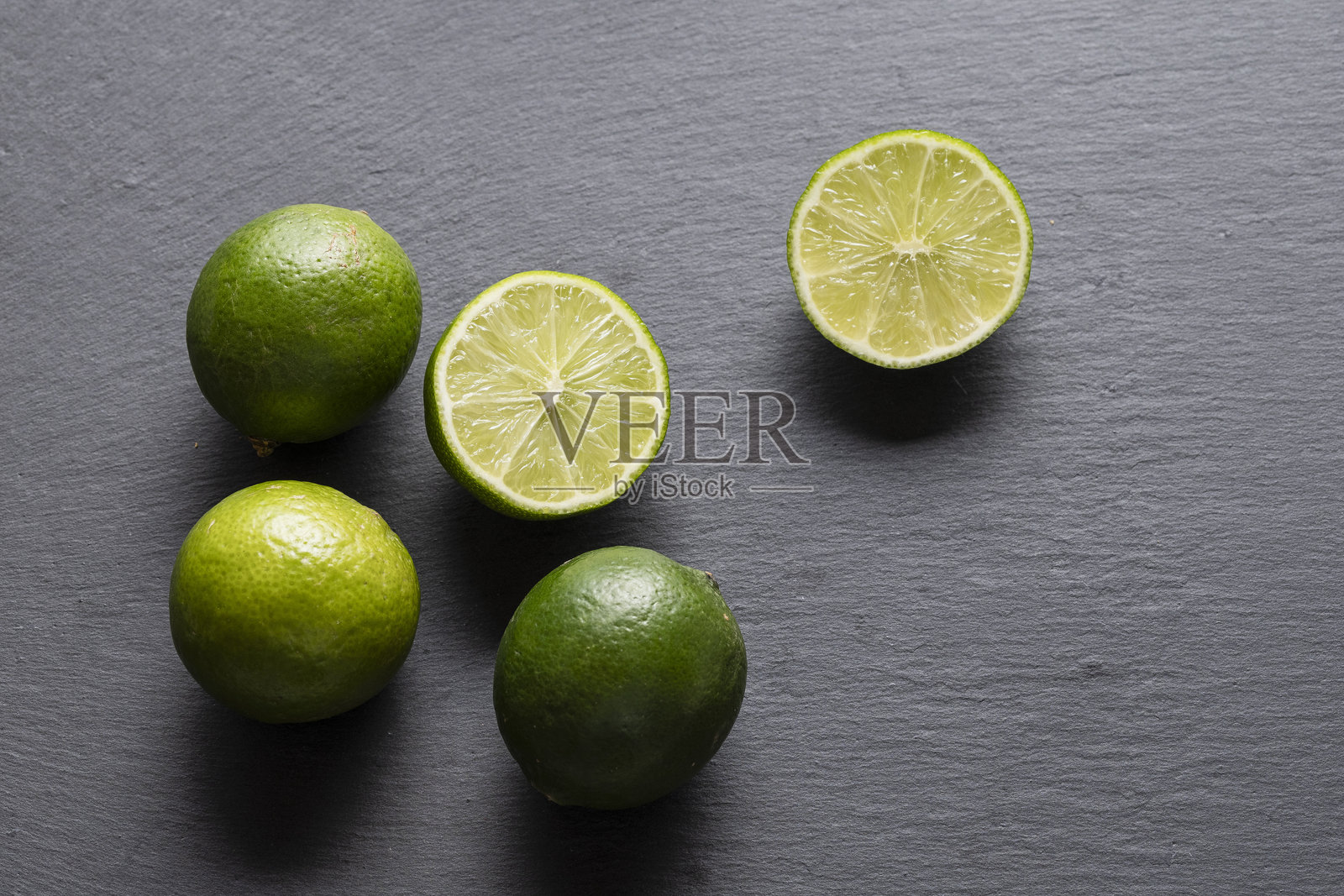 新鲜的绿色青柠在黑色石板背景上照片摄影图片