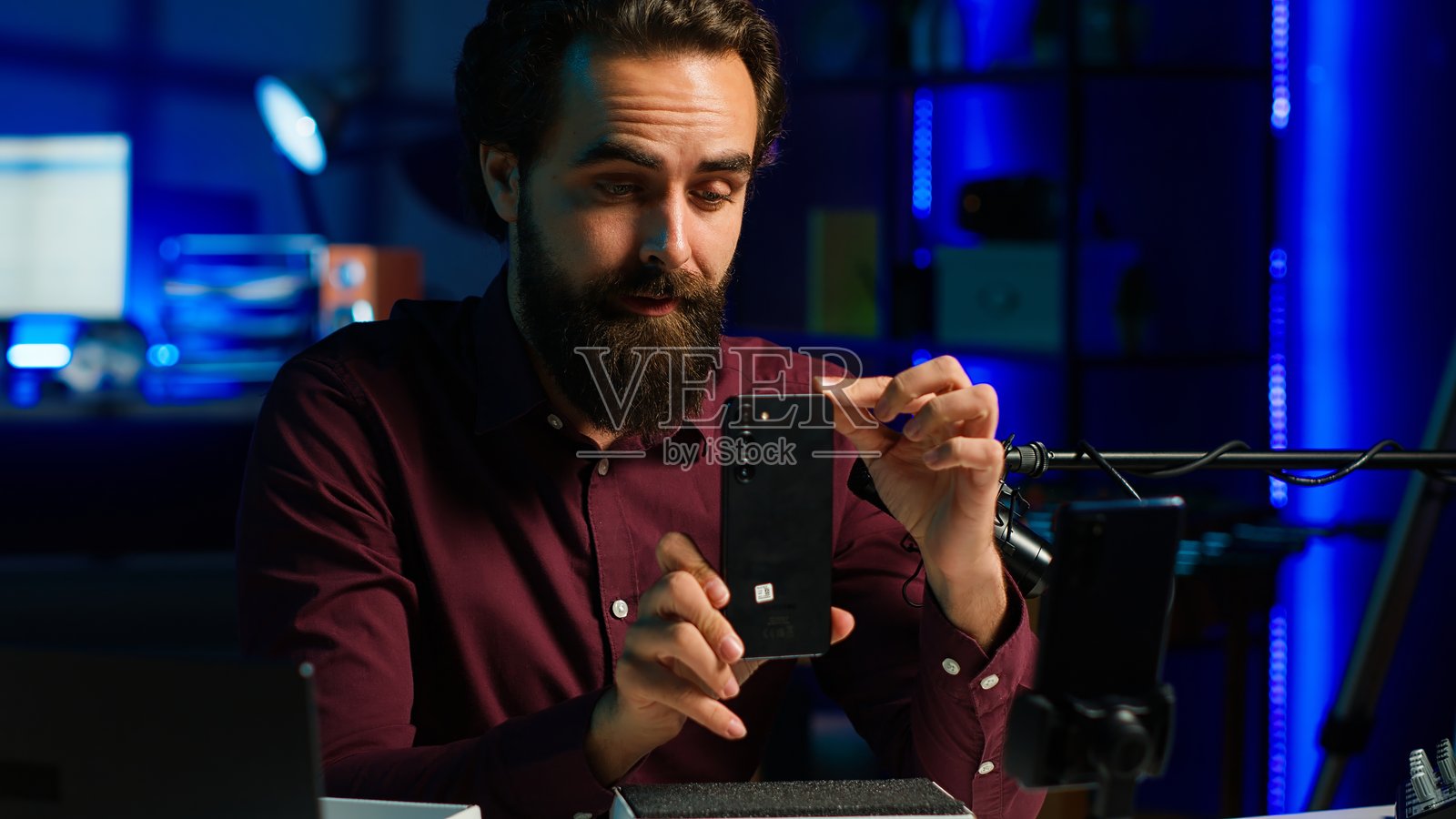 媒体明星在霓虹灯照明的工作室中展示品牌赞助视频的手机照片摄影图片