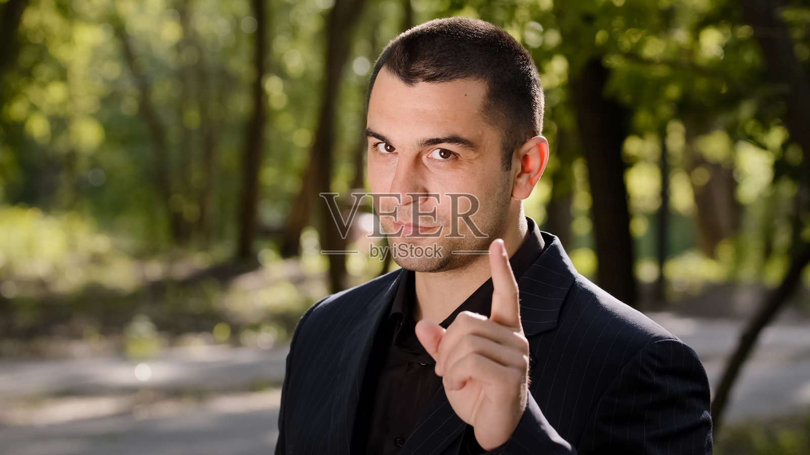 白人帅气的怀疑者男商人在城市街道户外站着,面向镜头摇手指以警告,表示不赞同的手势,禁止、训斥、反对的负面信号。照片摄影图片