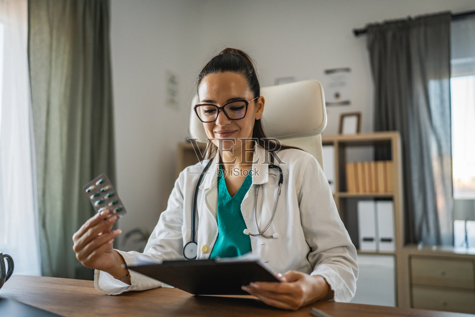女医生手持药物泡罩包装,夹着处方的文件夹照片摄影图片