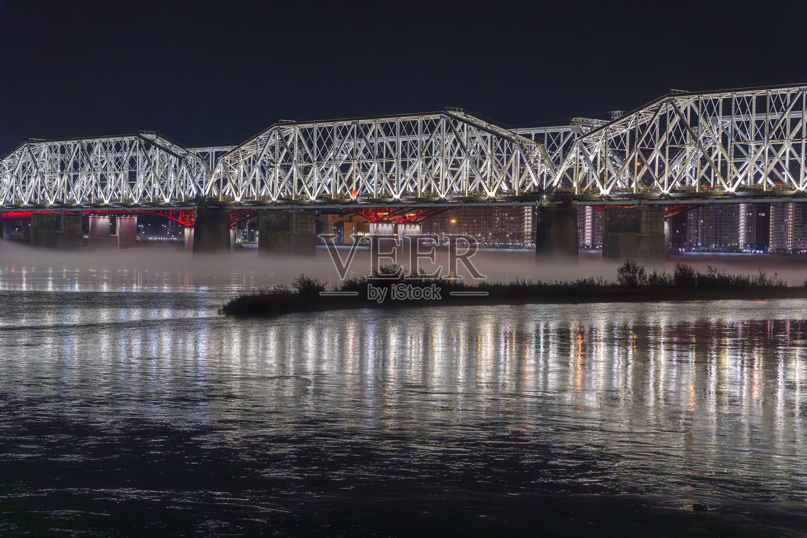 夜晚照亮的桥梁横跨河流,水面上倒映着光影照片摄影图片