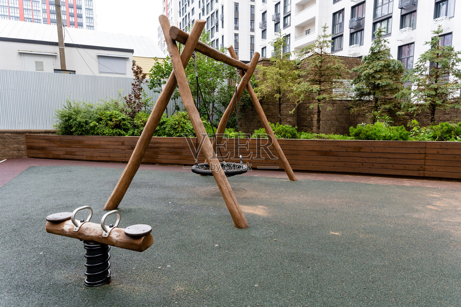 在一个充满活力的游乐场,迷人的木秋千架格外引人注目,背景中的建筑为该地区增添了特色和社区感。照片摄影图片