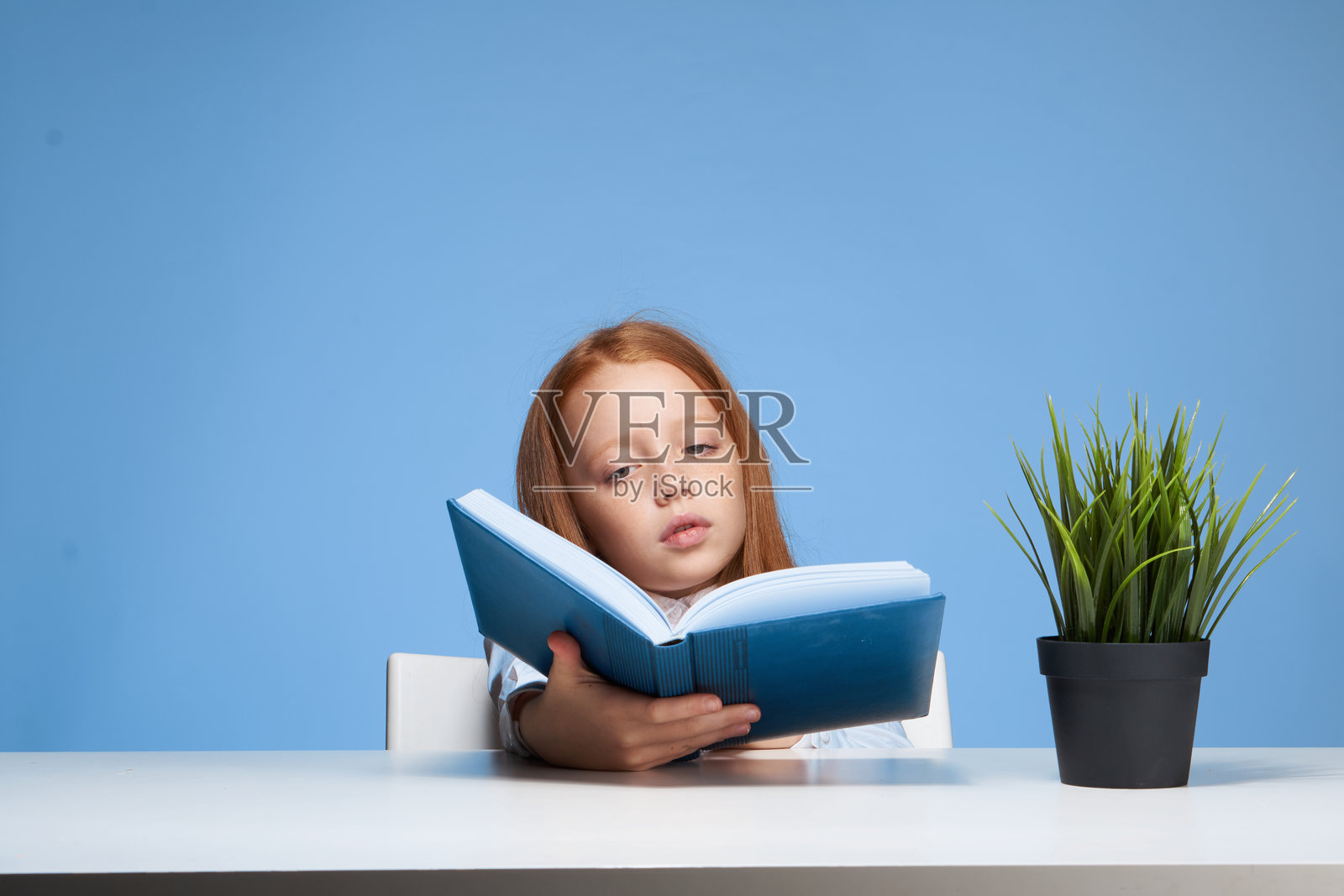 坐在桌子旁的女学生与书本,教育与童年照片摄影图片