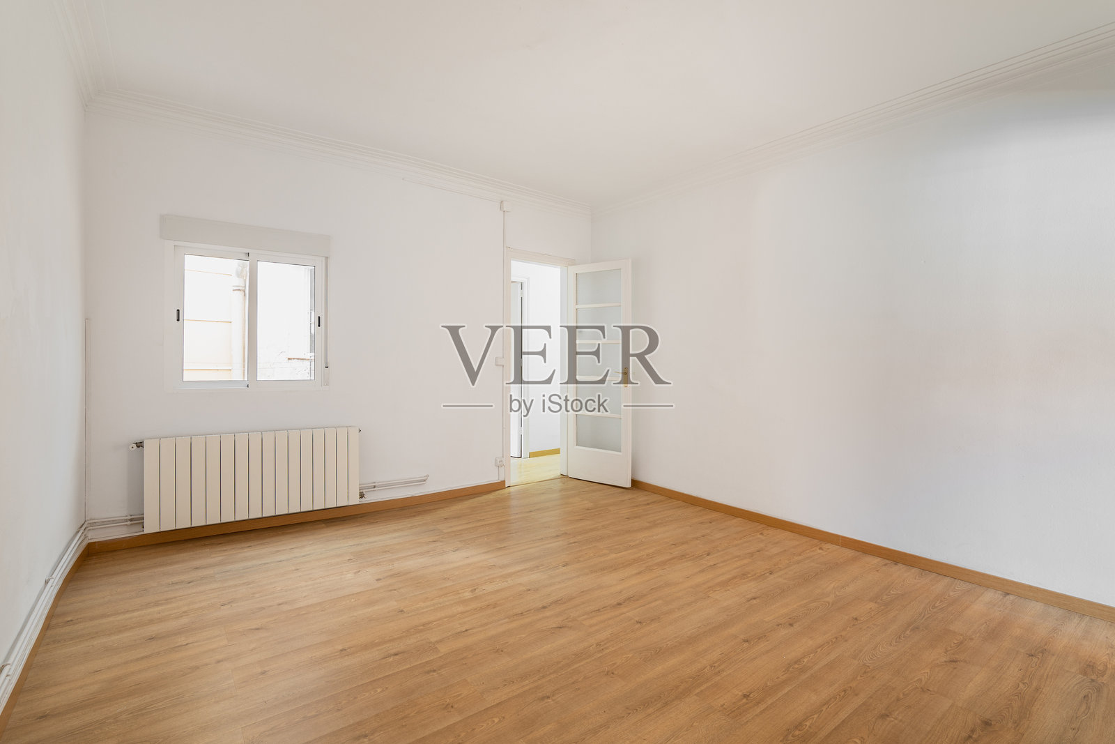 一个空白的白色房间,带有窗户和一个木质贴面入口门,位于乡村房屋中。新公寓或酒店房间度假的概念。留白空间。照片摄影图片