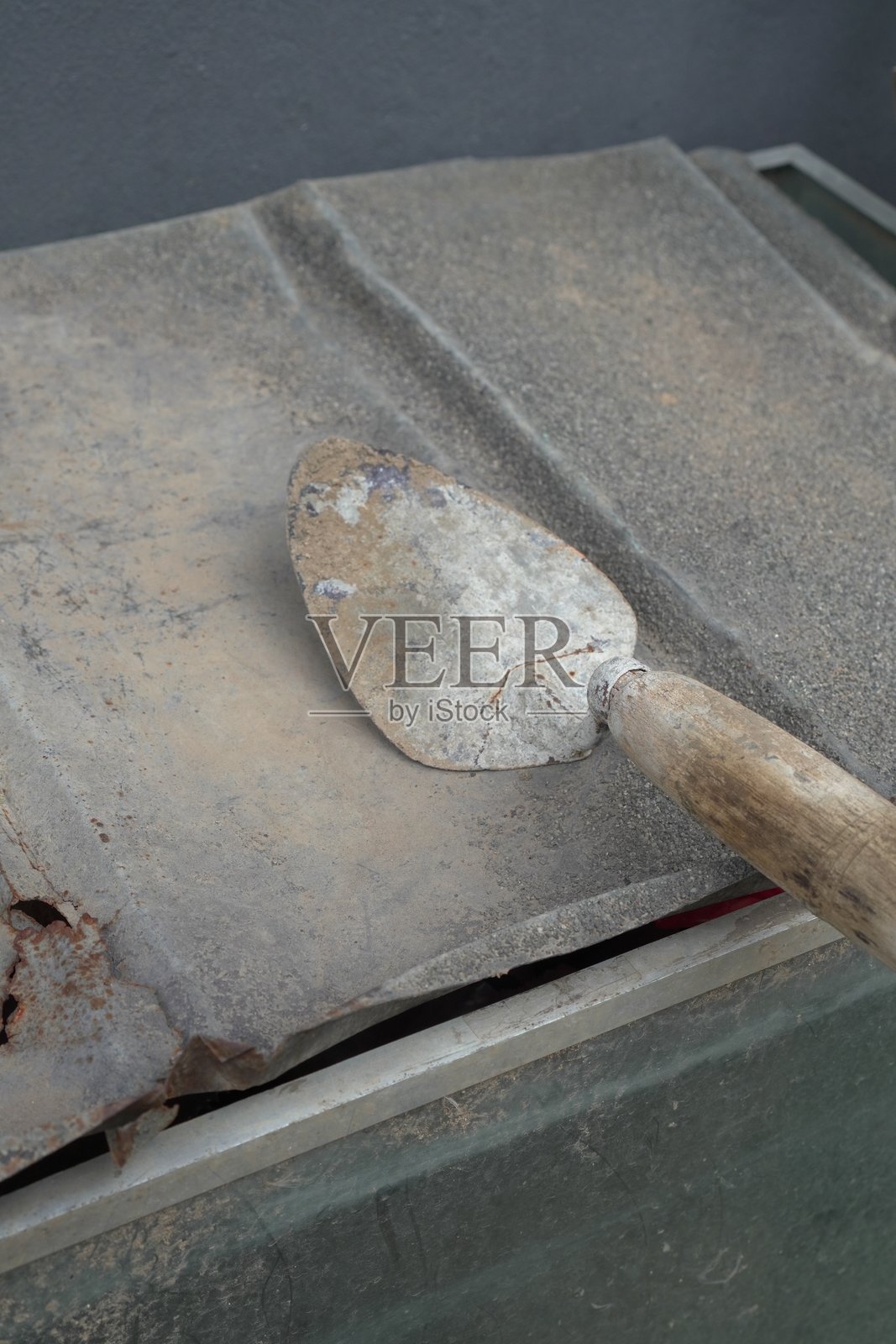 一把风化的铲子静静地放在一个有纹理的表面上照片摄影图片