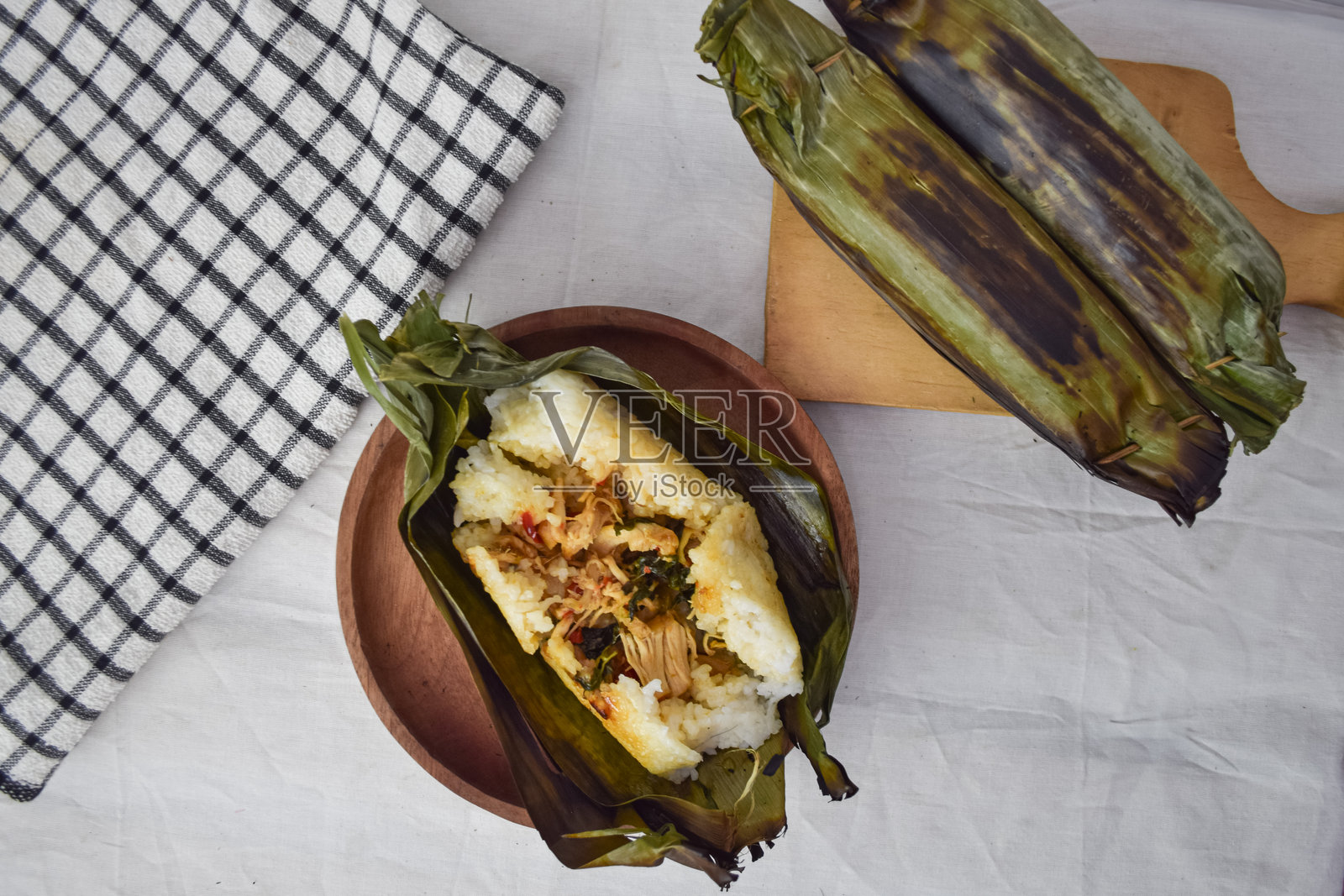 用香草和香料调味的烤米饭,传统印尼美食,展示了一道包裹在香蕉叶中的美味米饭菜肴。照片摄影图片