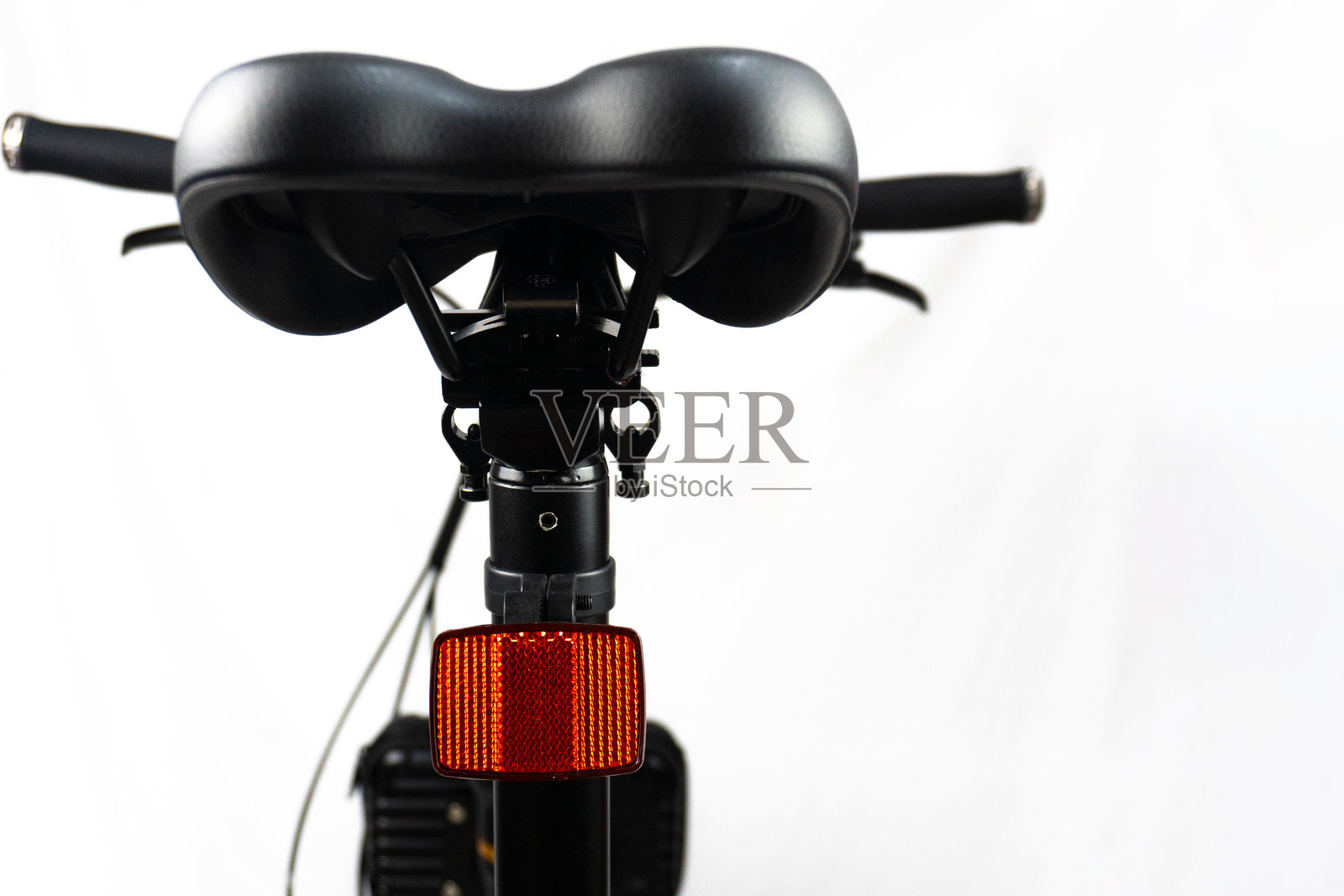 黑色自行车座椅的背面,黑色车把,背景为白色。照片摄影图片