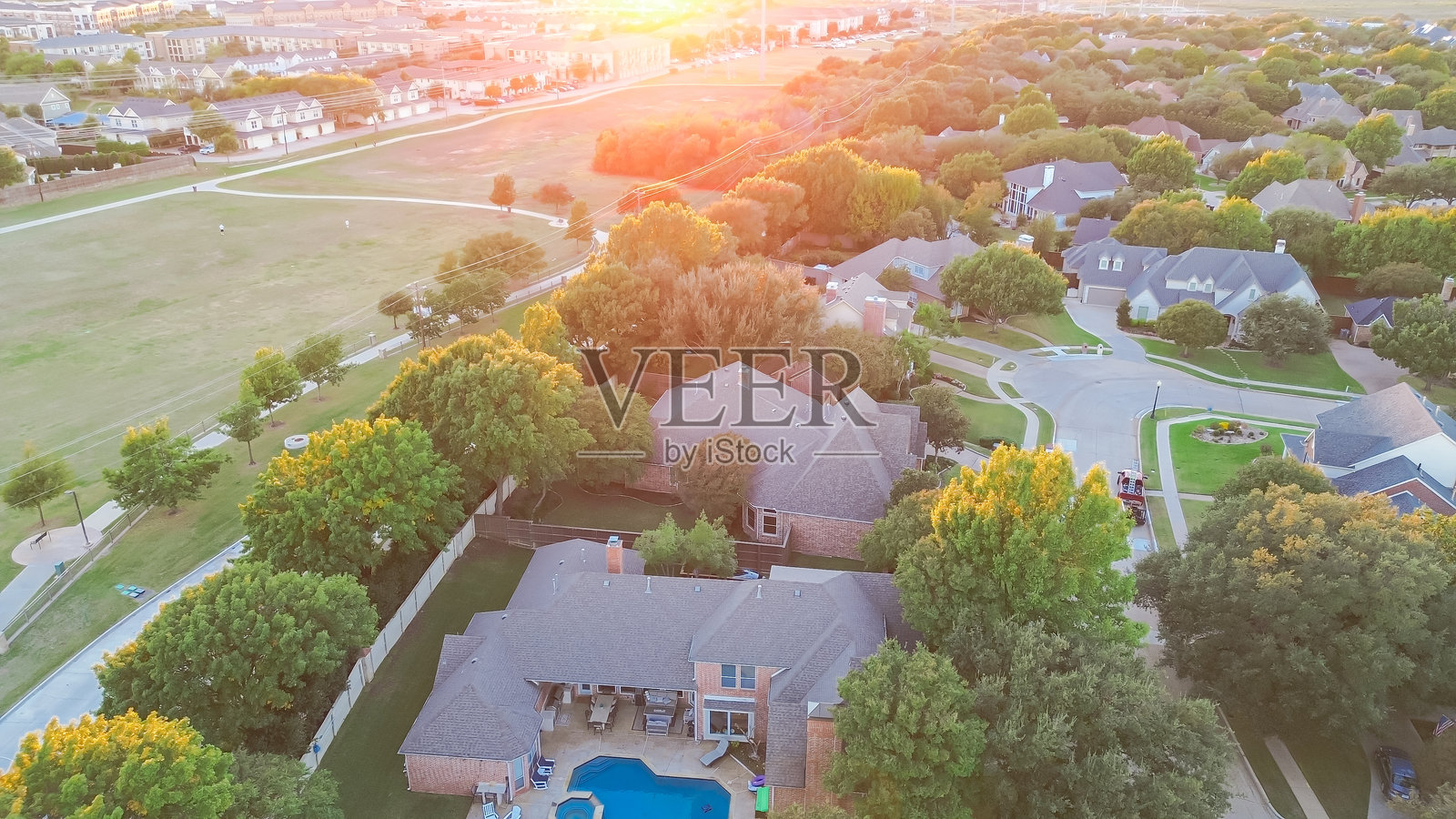 德克萨斯州普莱诺市中途公园附近的长混凝土步道,适合步行和骑行,周围是郁郁葱葱的绿地和高档住宅区,豪华别墅带游泳池,公寓楼,鸟瞰图。照片摄影图片