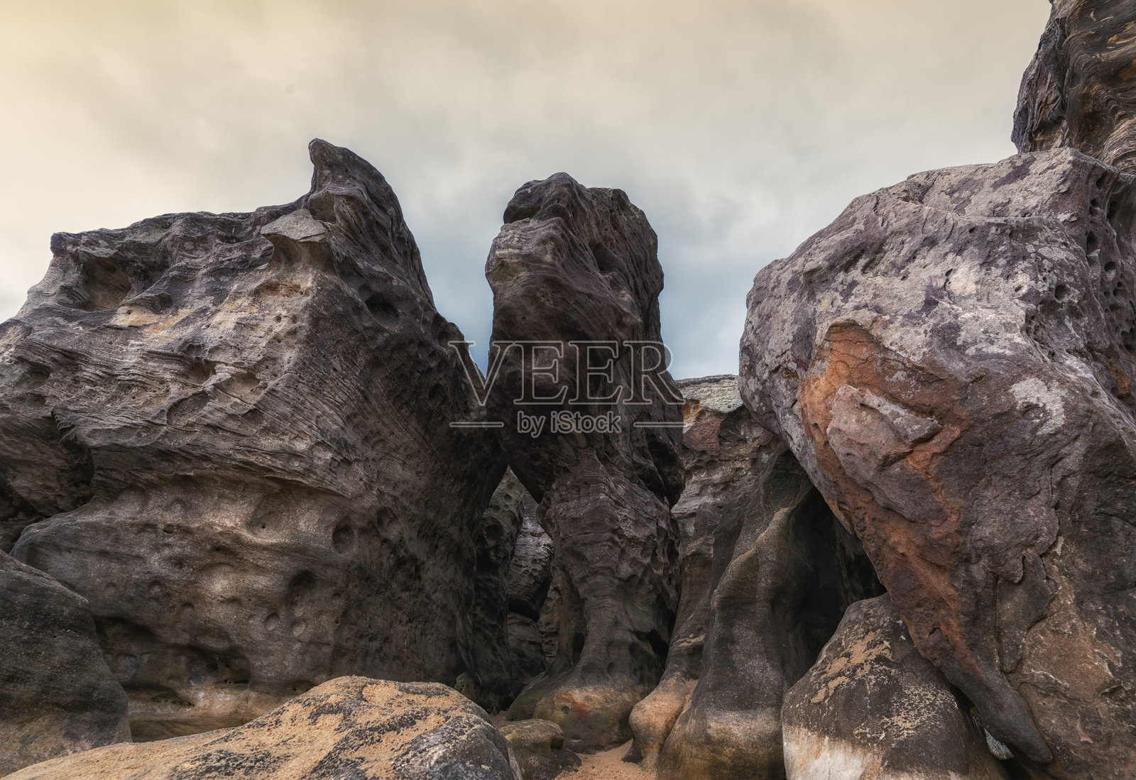 在灰色天空下,古老岩石的粗糙形状和纹理展示了自然的严酷与壮丽之美。照片摄影图片