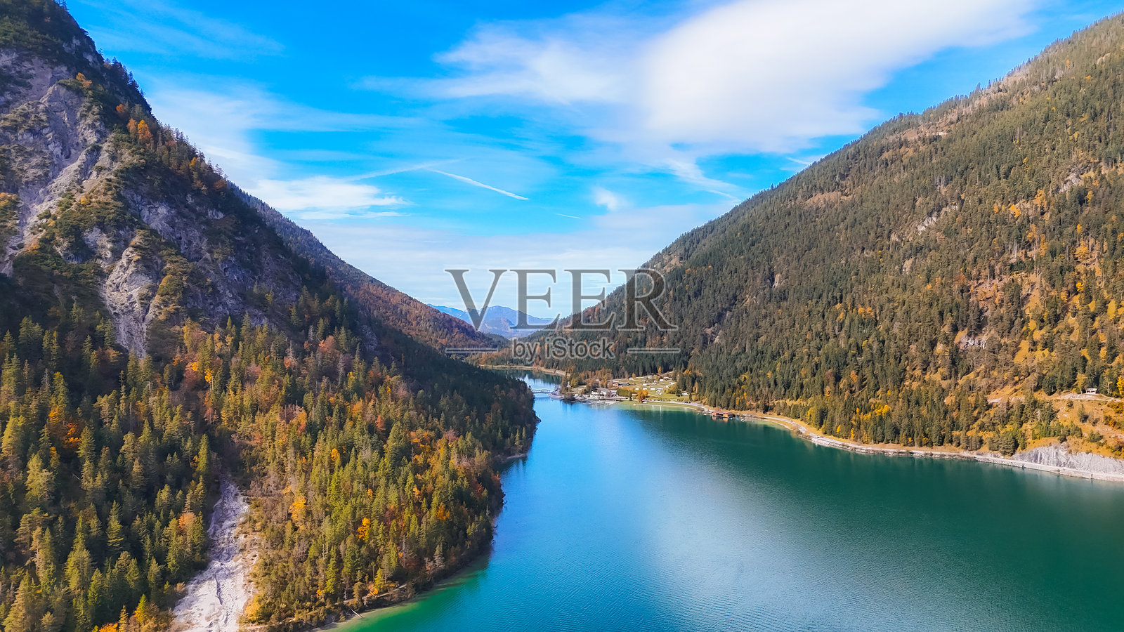 探索欧洲迷人的秋季湖泊。游客在一个宁静的湖边欣赏周围山脉的绚丽秋色,享受美丽的欧洲目的地。照片摄影图片