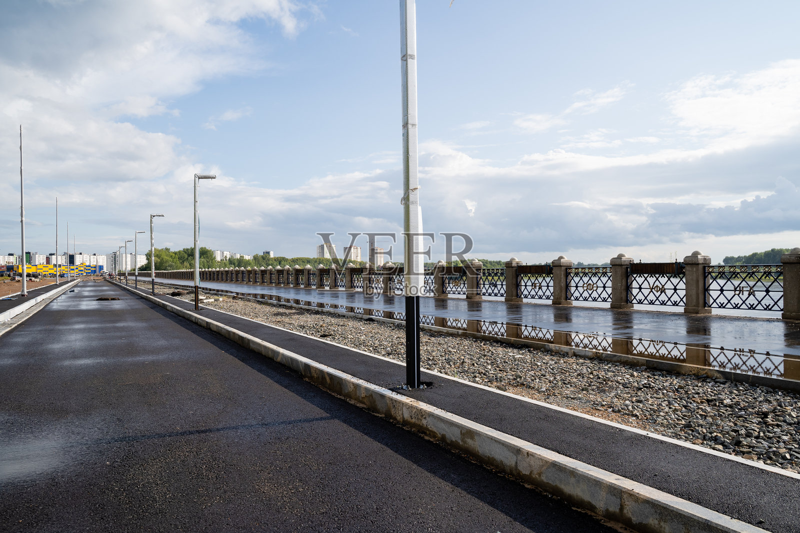 一幅画面描绘了一条宁静的道路,旁边是一道坚固的围栏,背景是一片宁静的水域。这幅如画的场景唤起了一种平和的感觉。照片摄影图片