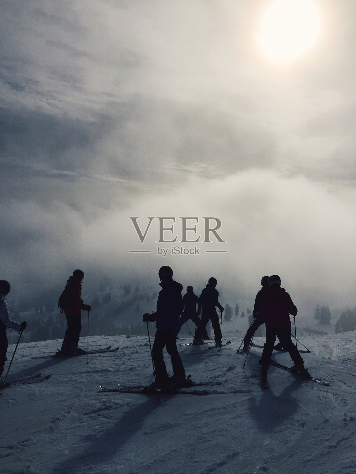 雪山上滑雪者的剪影与多云的天空相映衬照片摄影图片