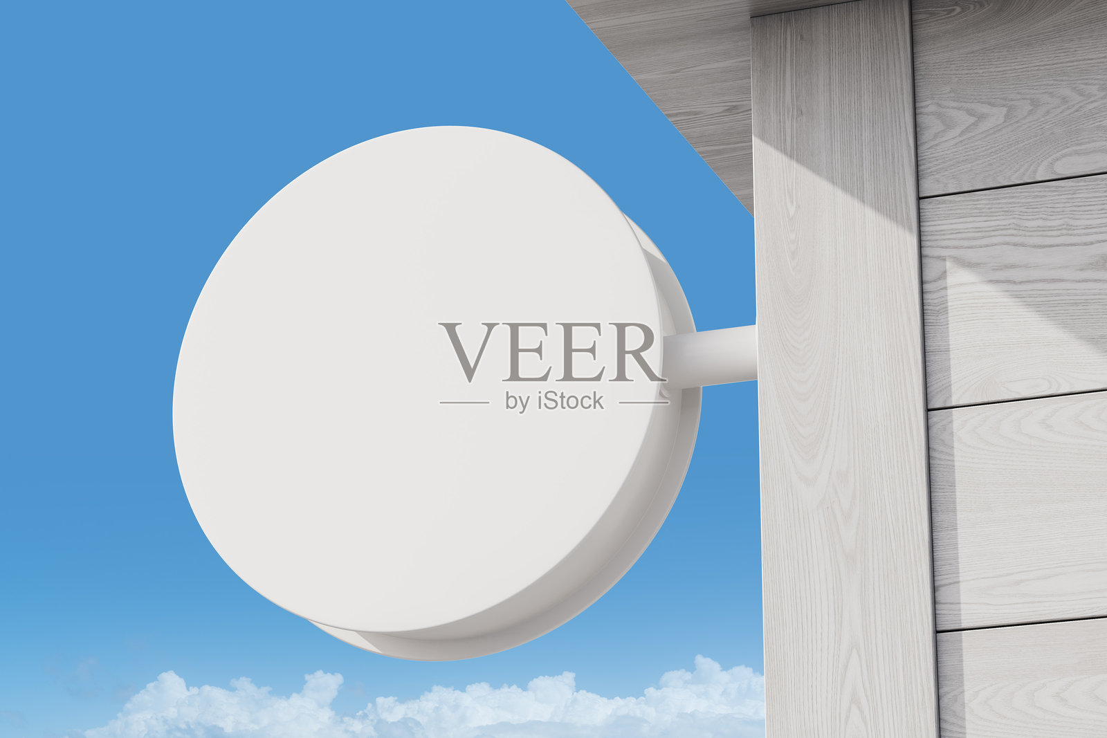 一个圆形空白户外标志模型安装在浅色木质外立面上,背景是晴朗的蓝天。户外广告展示的概念。3D渲染。照片摄影图片