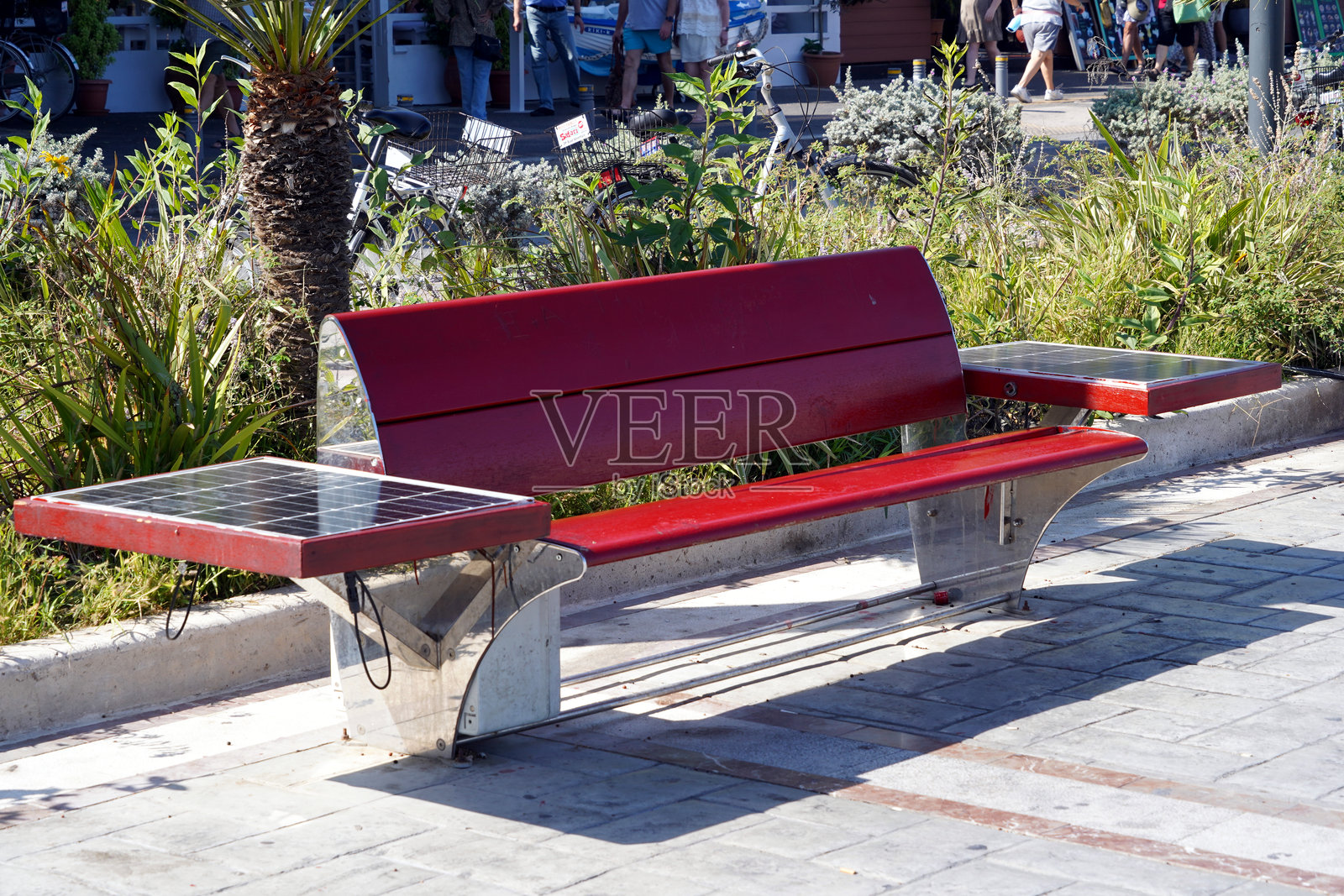 一张配备太阳能光伏板用于手机充电的红色木制长椅。照片摄影图片