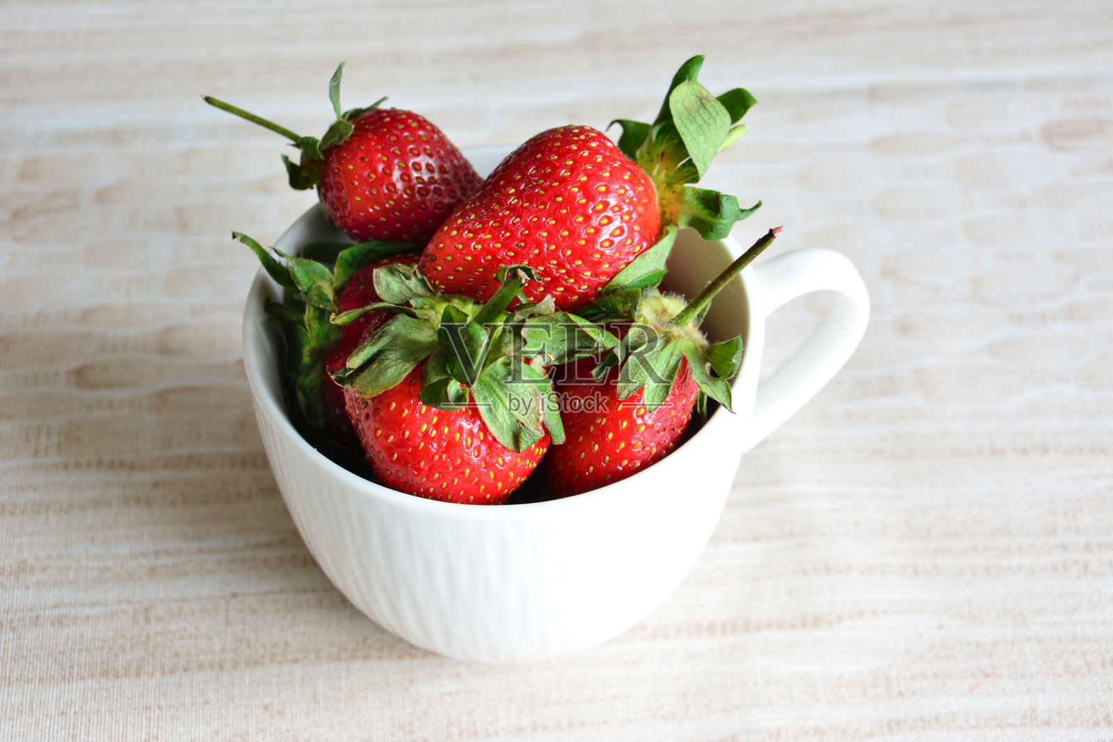 一个装有草莓的白色陶瓷杯特写照片摄影图片