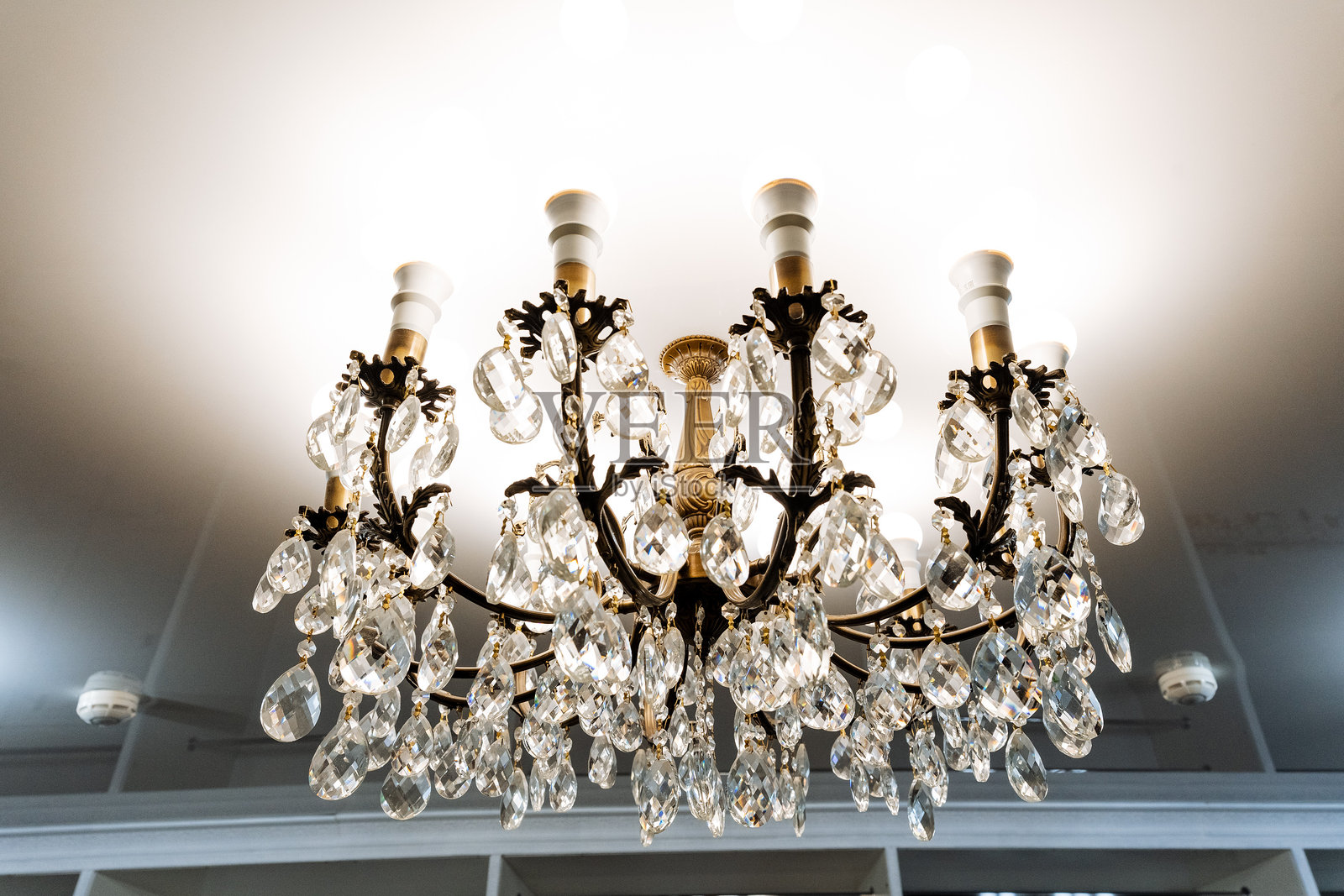 一盏精美复杂的华丽吊灯优雅地悬挂在宽敞房间的高天花板上,显著提升了整体装饰的精致感和优雅魅力。照片摄影图片