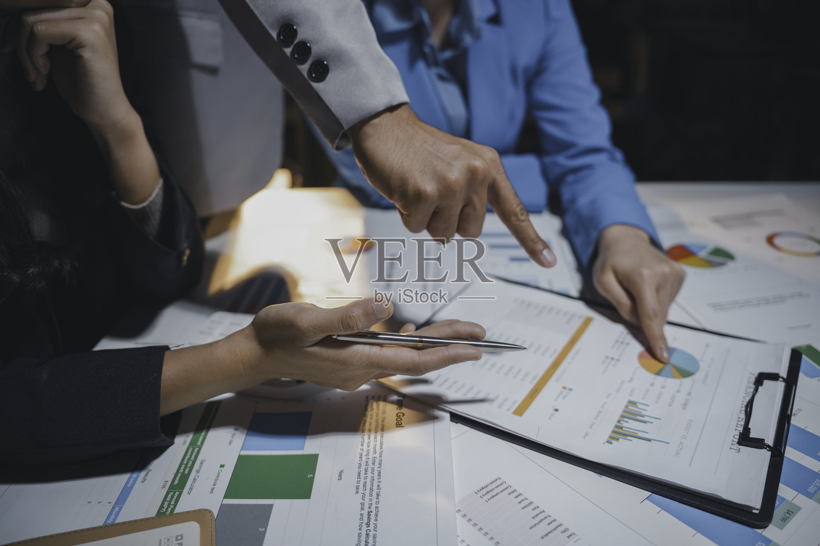 商务团队加班,分析财务文件并指着图表和图形照片摄影图片