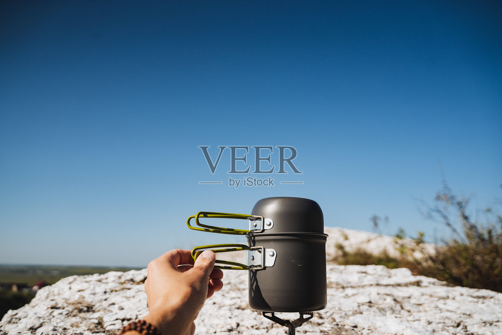 一个人小心翼翼地在一块大石头上平衡着一个锅照片摄影图片