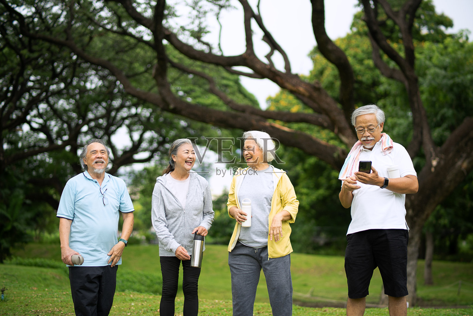 一群老年人在公园里锻炼和玩智能手机。照片摄影图片