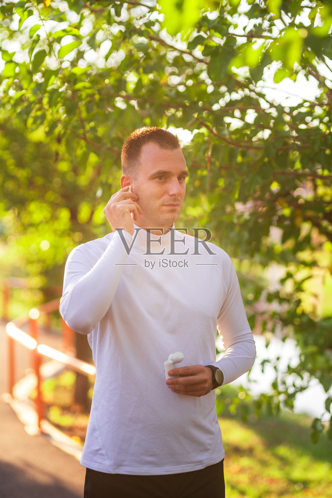 年轻运动员在公园跑步前戴上无线耳机照片摄影图片