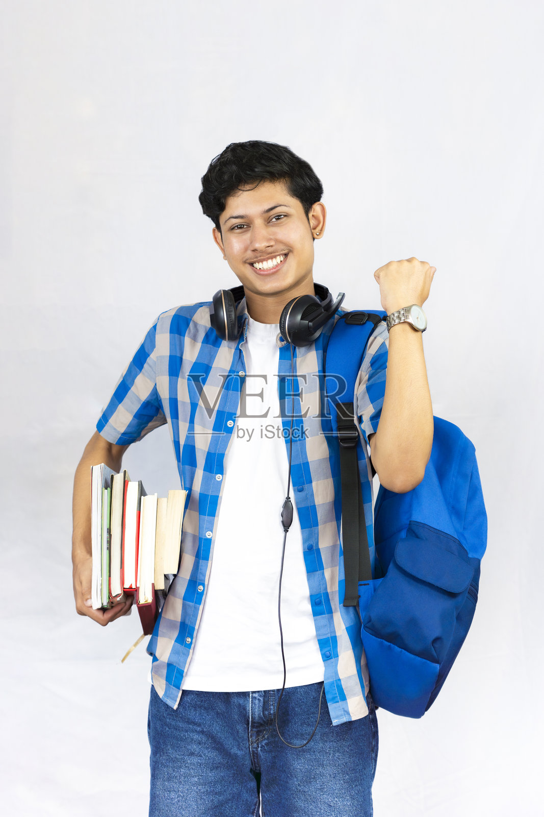 年轻男性留学概念,背着包,手持书籍和耳机,表情丰富,手势生动的学生照片摄影图片