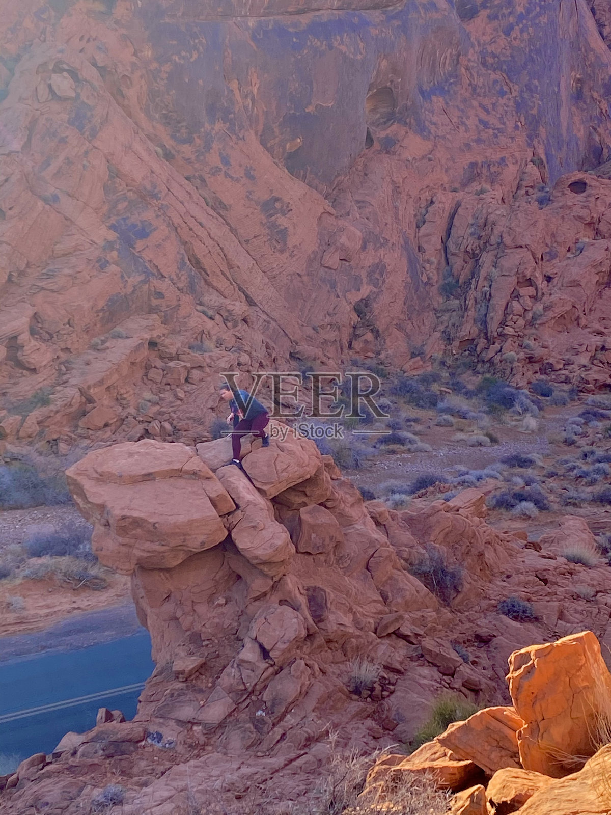 在美国内华达州火焰谷州立公园攀爬红色岩石的女性照片摄影图片