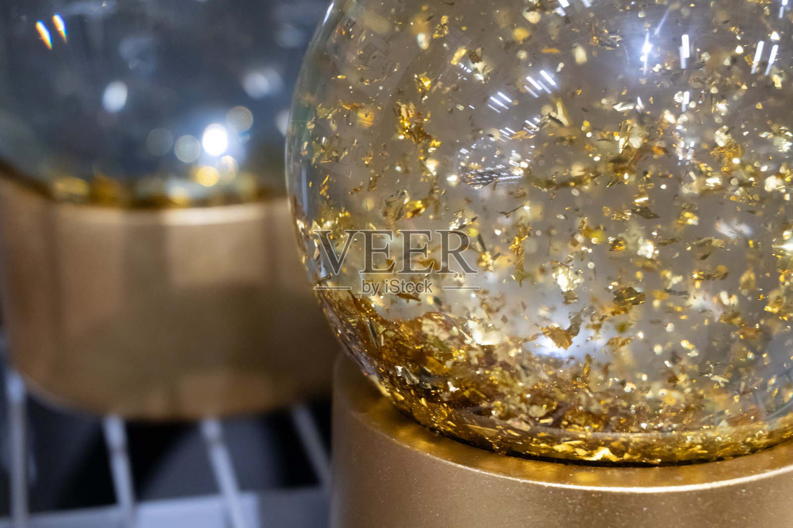 一个内部有金箔的雪花球。这个透明的球体充满了闪烁的颗粒,体现了和谐与庆祝。照片摄影图片