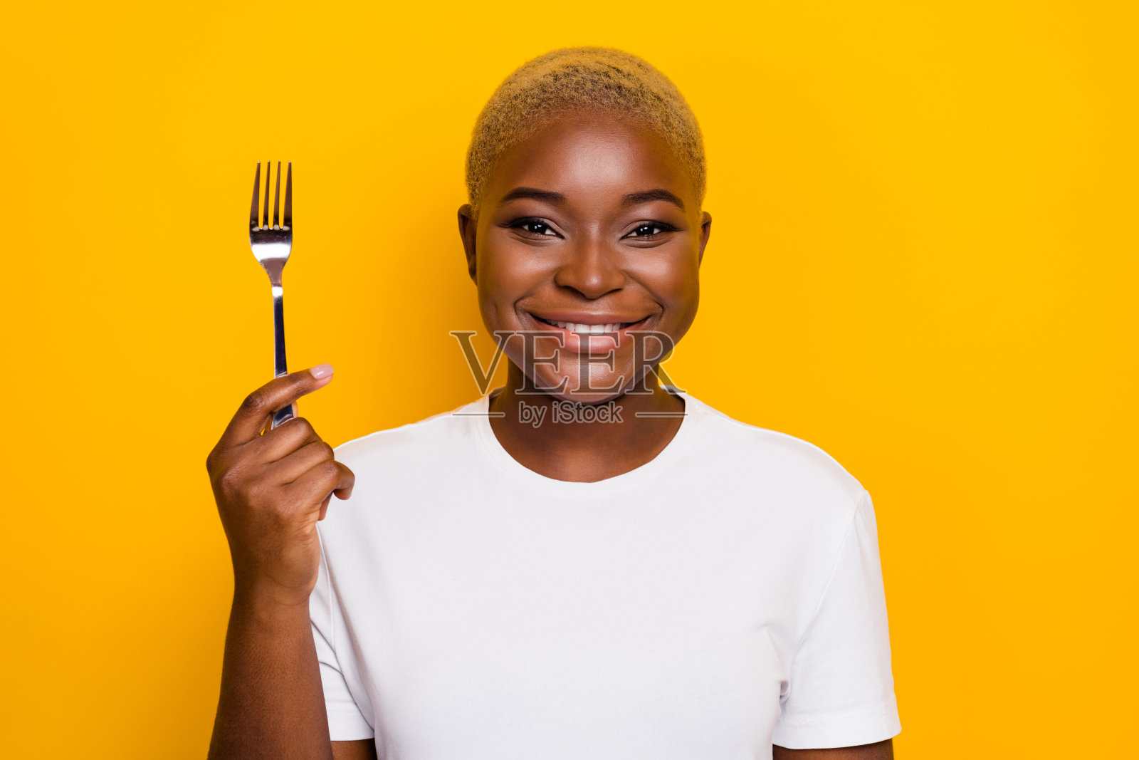 可爱的有趣女士手持叉子,准备享用美味的健康饮食,背景为黄色。照片摄影图片