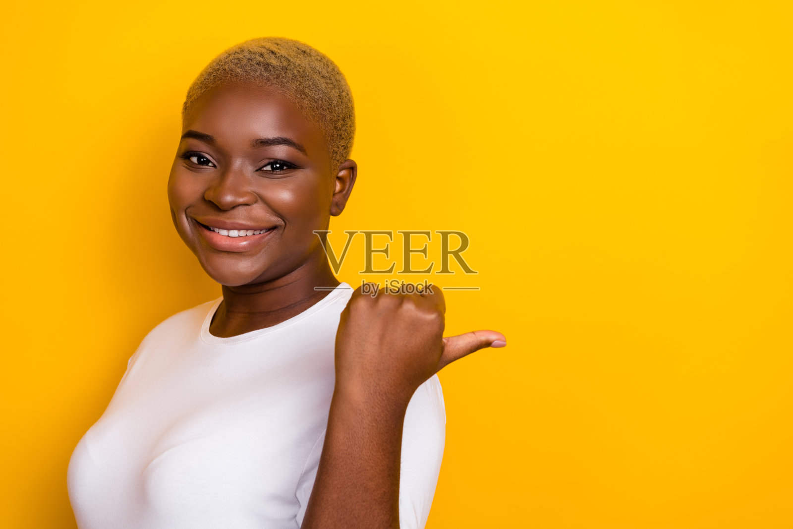 迷人的女士特写侧脸照片,穿着时尚的白色服装,手臂和手的拇指在黄色背景上留有空白空间。照片摄影图片