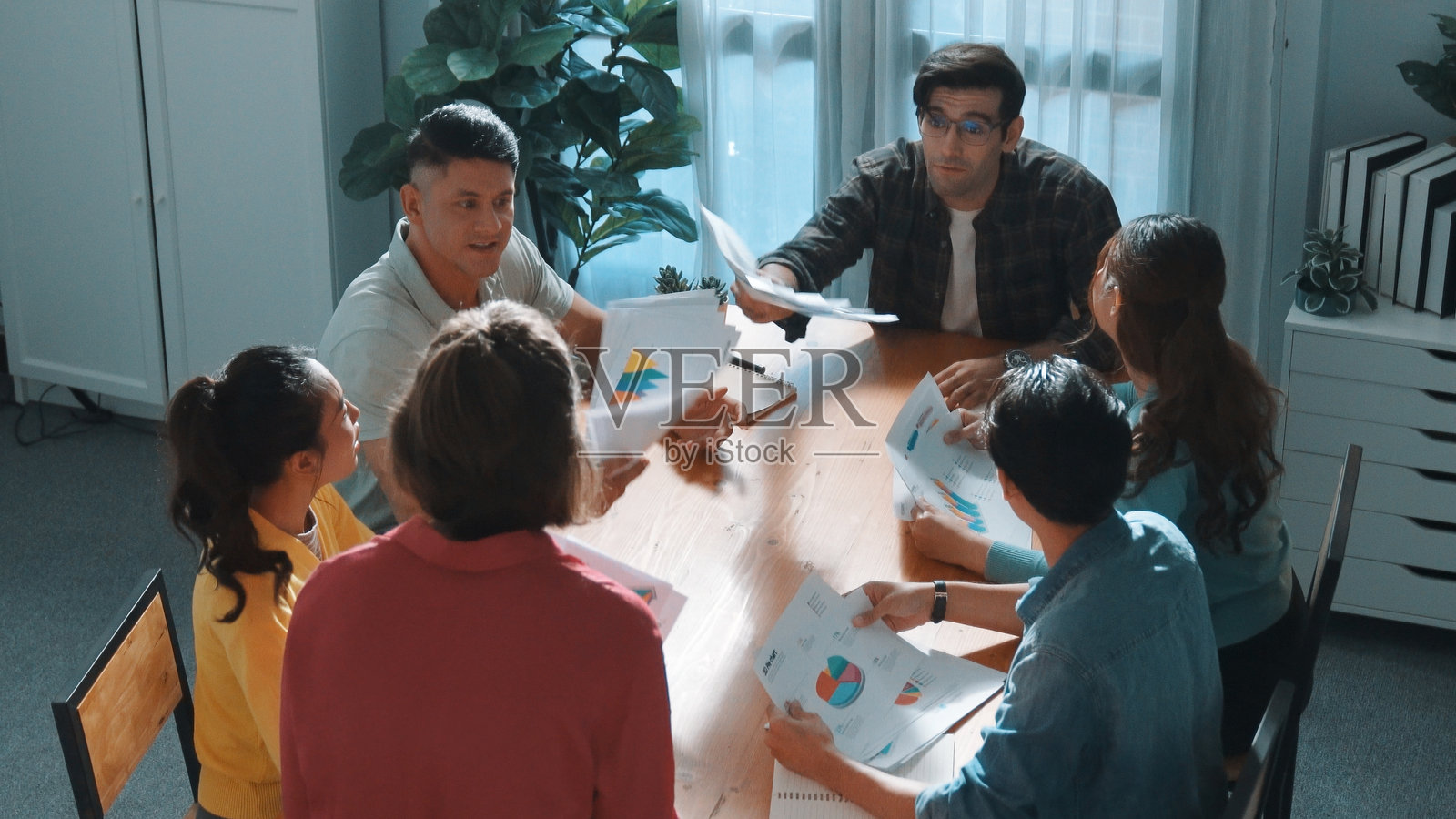 从上方俯视创业团队讨论创意时手持纸张的场景。研讨会。照片摄影图片