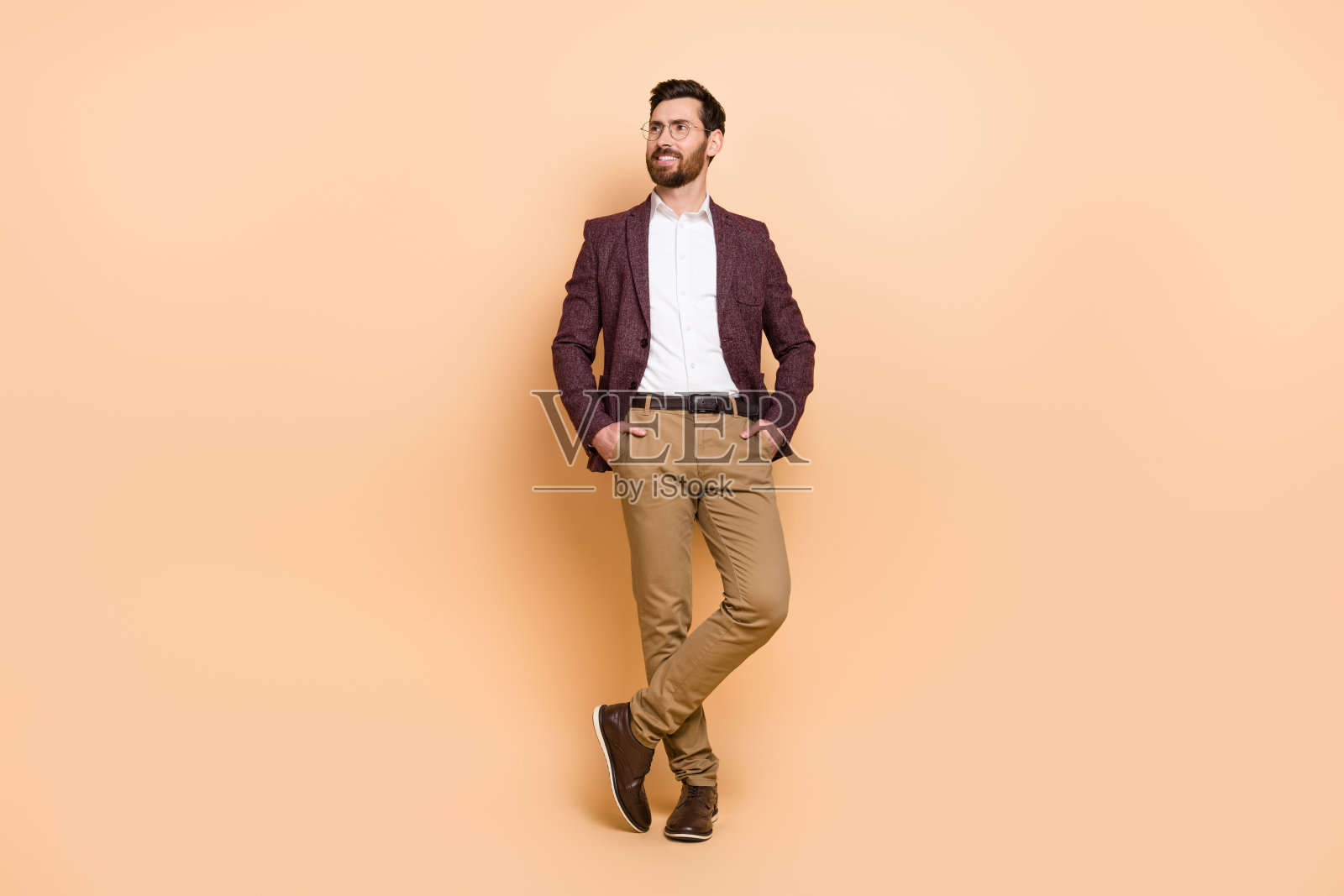 全身照的帅气商人看到他的公司服务推广,背景为米色。照片摄影图片