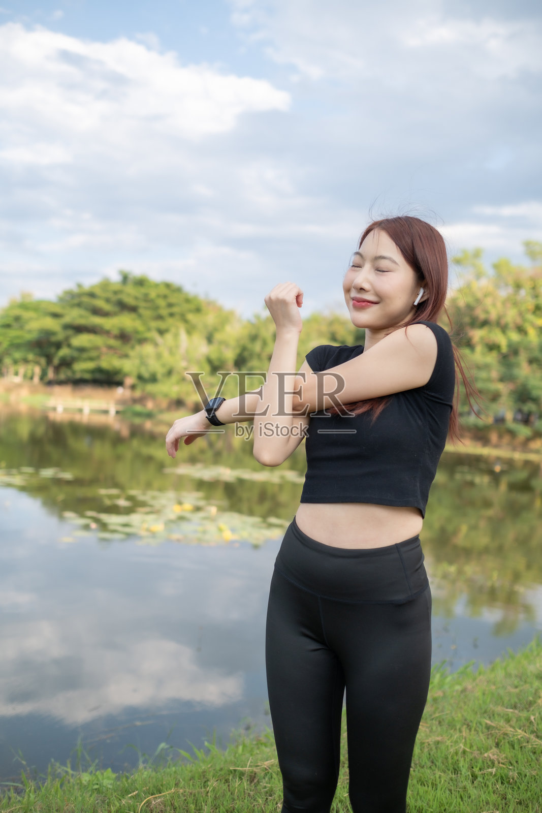 一位女性在湖边的公园里伸展身体照片摄影图片