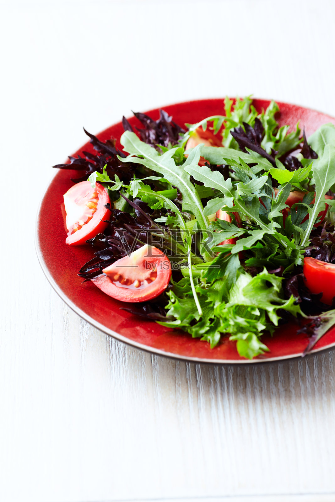 新鲜番茄和芝麻菜的沙拉,背景为明亮的石材。特写。留白。照片摄影图片