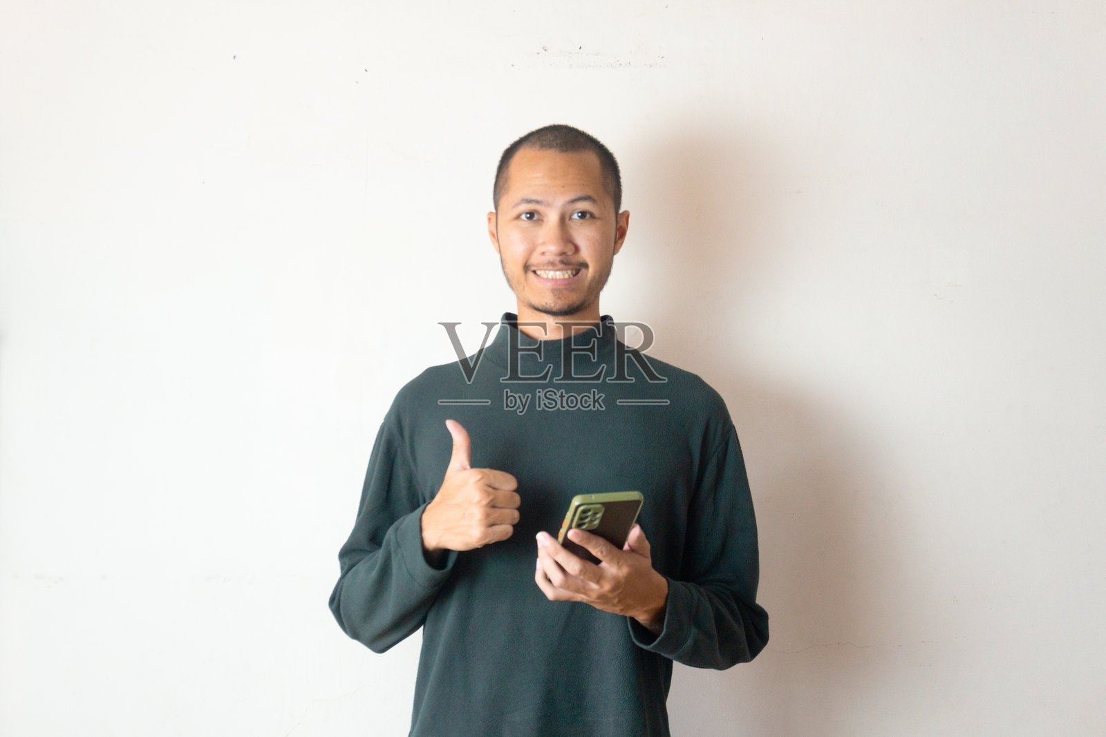 穿着绿色毛衣的年轻男性在白色背景上推荐应用程序照片摄影图片