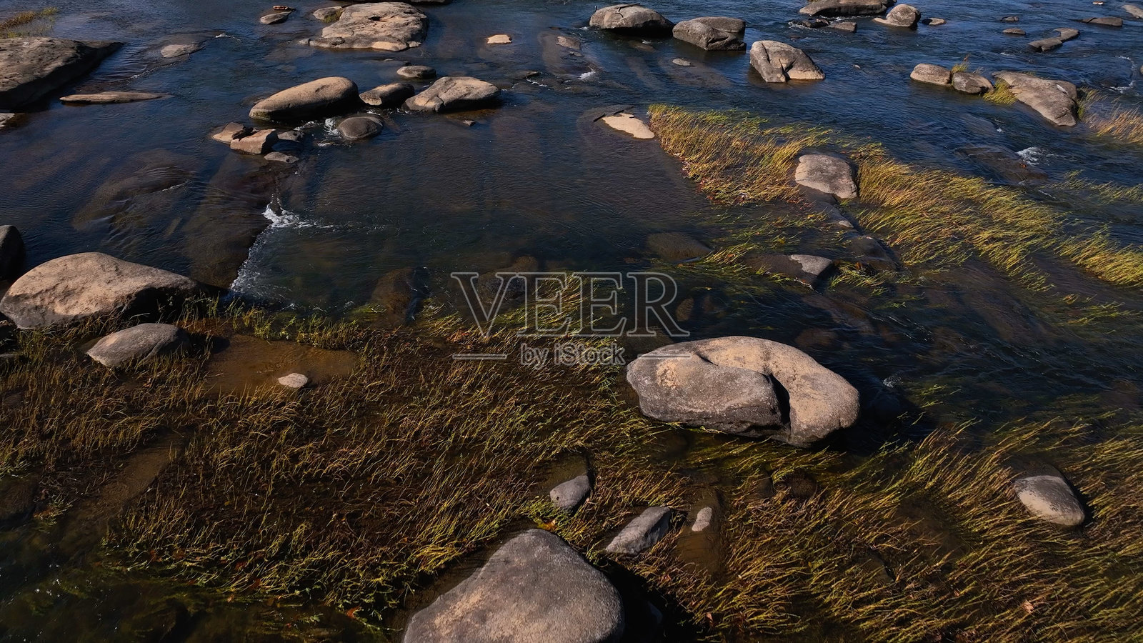 在弗吉尼亚州里士满附近的詹姆斯河,阳光下宁静的河流,水中有温和的急流和岩石,适合水上运动,河岸旁有徒步和骑行小径。照片摄影图片