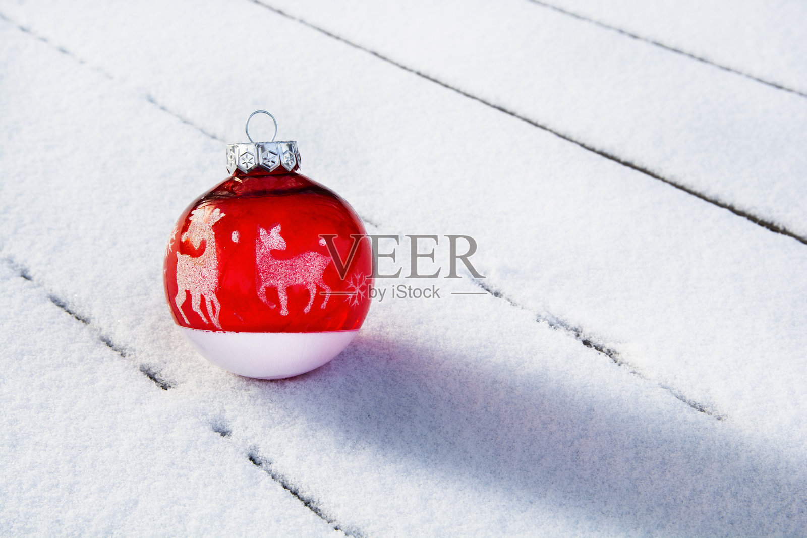 红色圣诞树球与鹿在雪白的木质背景上。适合圣诞贺卡的背景。照片摄影图片