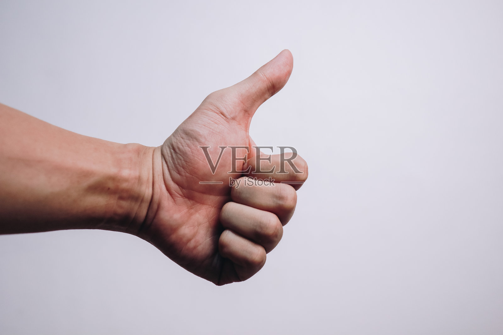 白色背景上的人类手掌竖起大拇指。照片摄影图片