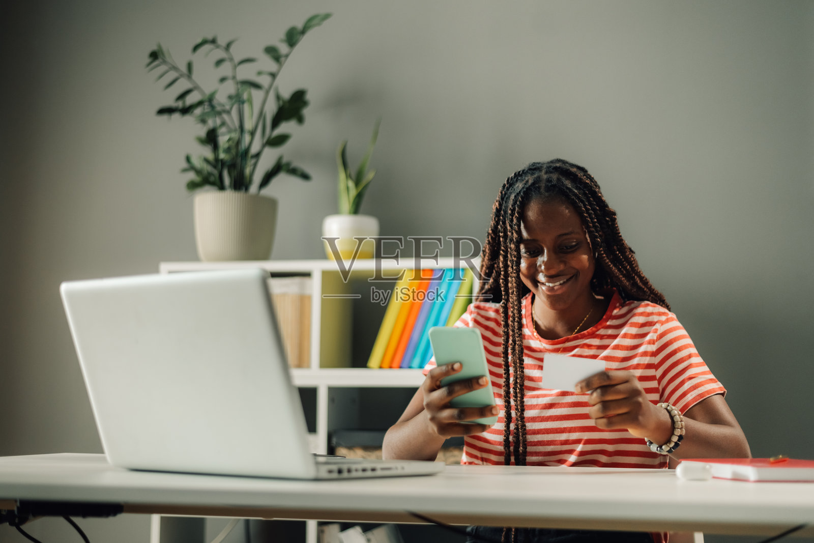 微笑的年轻女性正在使用智能手机和信用卡进行在线支付照片摄影图片