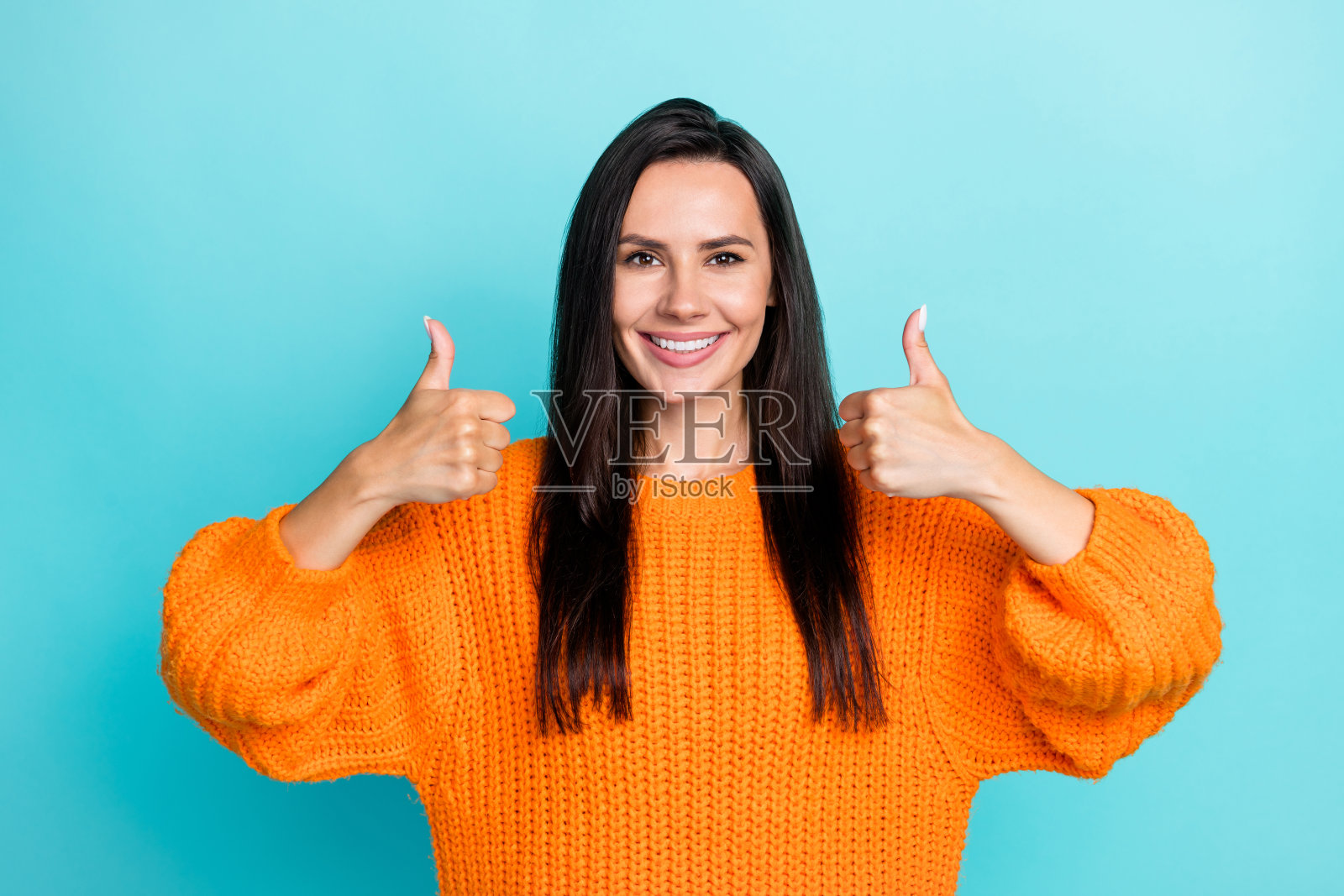 快乐女孩的手指竖起大拇指,表示“好”,背景为翡翠色。照片摄影图片