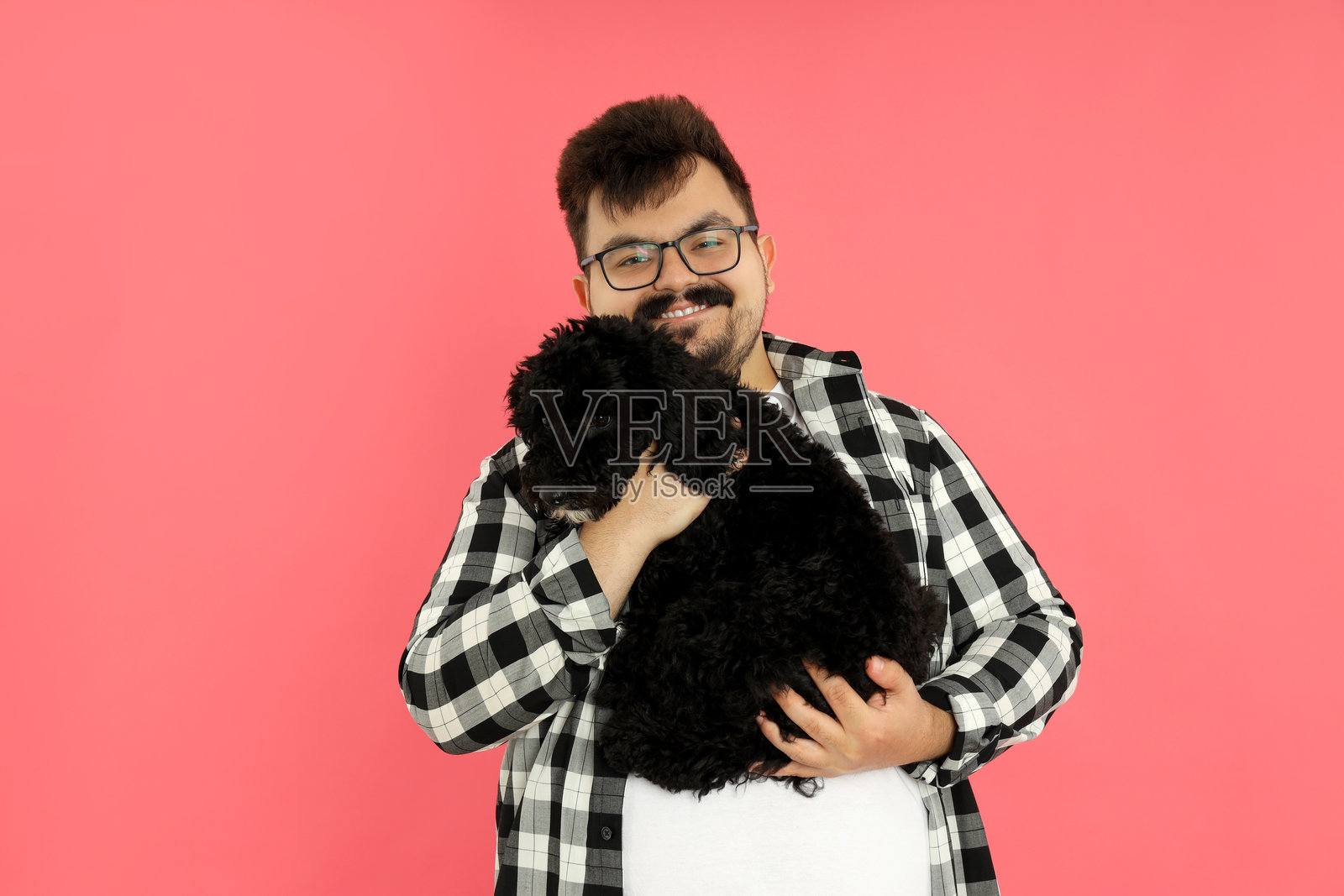 一名男子与一只狗在粉色背景上。照片摄影图片