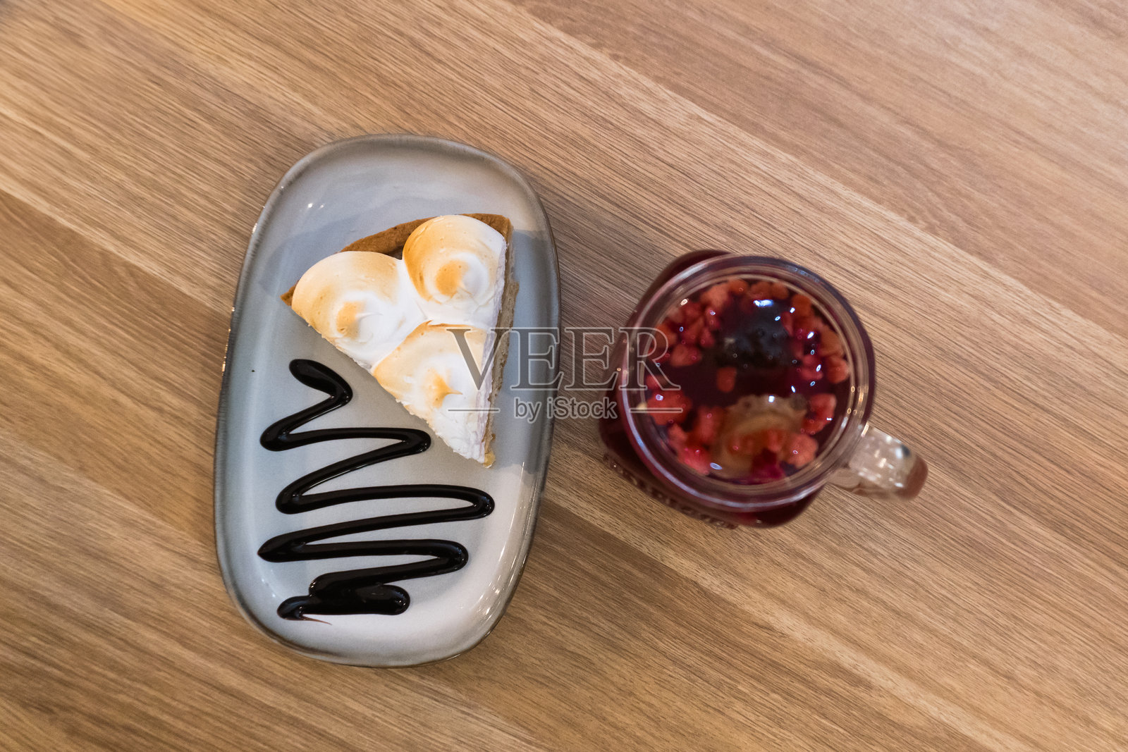 柠檬蛋糕配有柔软的蛋白霜和清新的柑橘馅,旁边是一杯覆盆子姜茶,背景是木质桌面。照片摄影图片