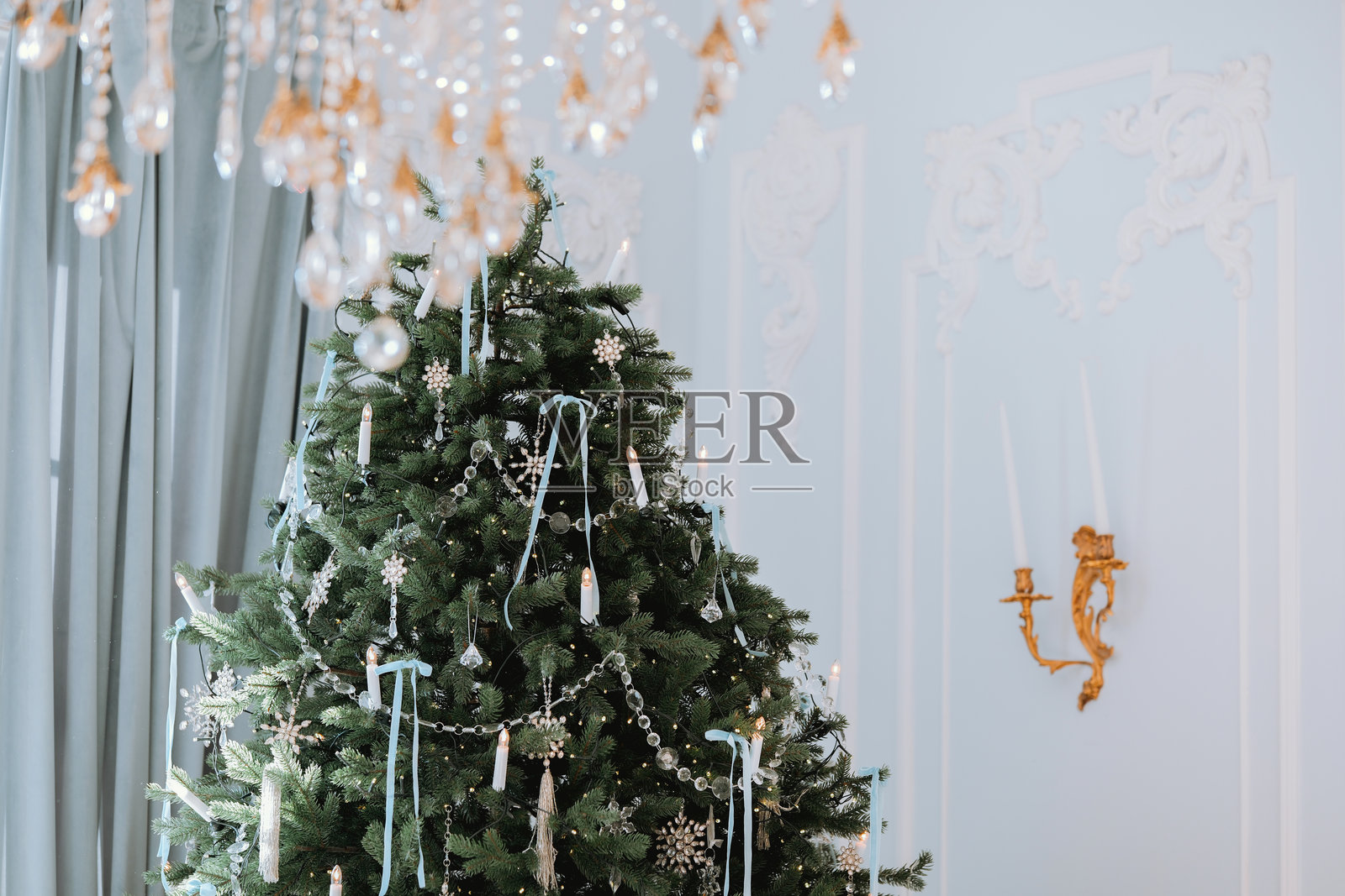 优雅的圣诞树装饰着蜡烛和饰品,置身于一个节日气氛浓厚的房间里照片摄影图片